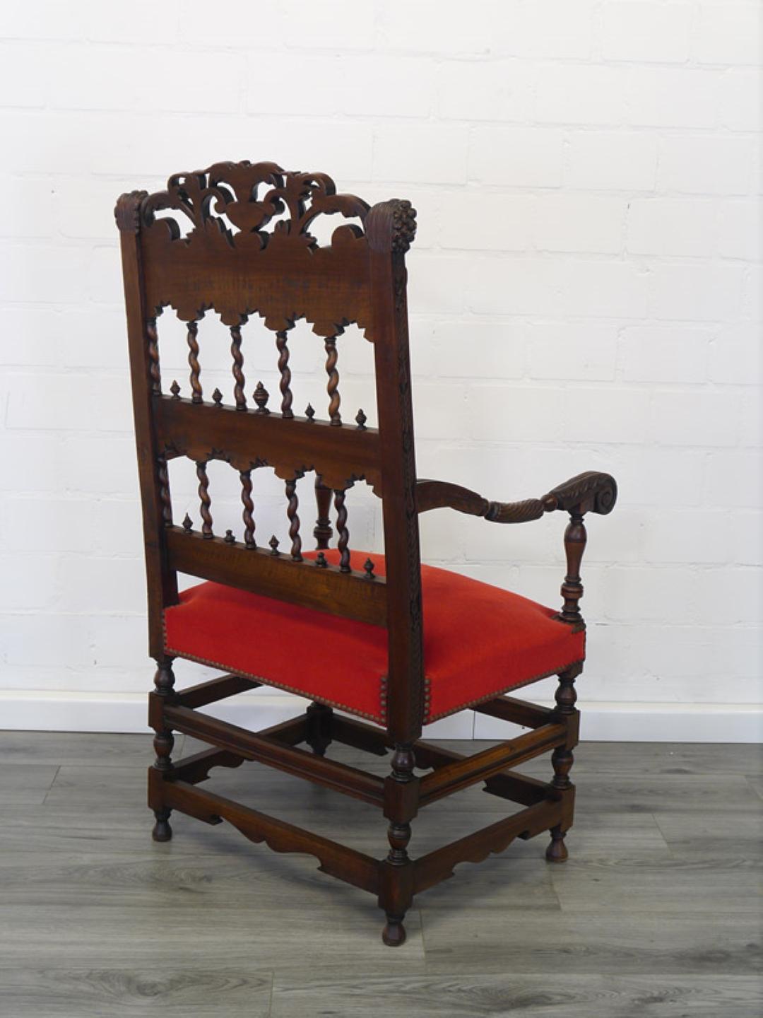 Classic antique armchair with a Renaissance design from the Revival period circa 1880. Made out of solid walnut wood and covered with a red velvet upholstery with round headed nails. The backrest if decorated with stunningly carved ornamentations,