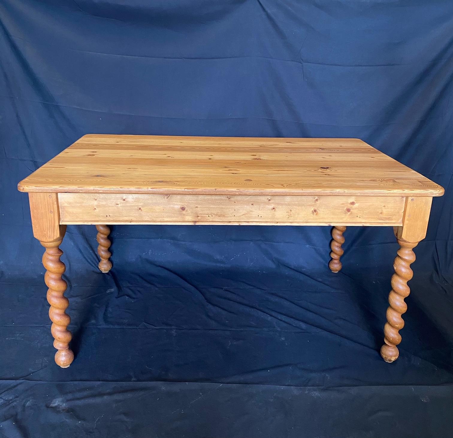 Antique country British farmhouse dining table or kitchen island hand crafted from pine planks on the top with tongue and groove joinery and two drawers on one side. The wonderful and rare thick turned barley twist legs have wood peg joinery. The