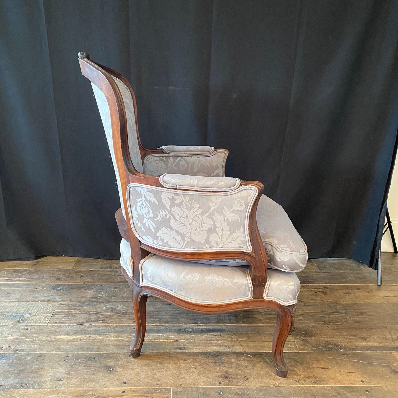 A lovely and very comfortable early 20th century French Louis XV style bergère armchair having beautifully carved walnut wood with loose shaped feathered cushions and curved legs. Lovely shape with great proportions and nice high quality upholstery.