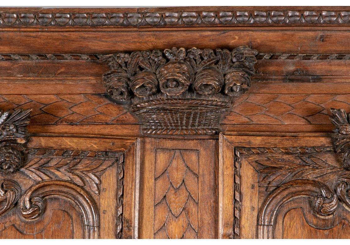 A large very well carved and authentic French Armoire. A fine bonnet over a flower basket crest (the flowers are loose but preserved) over double shaped doors with carved leafy floral crests (some chips) and floral details. With lovely carved leafy