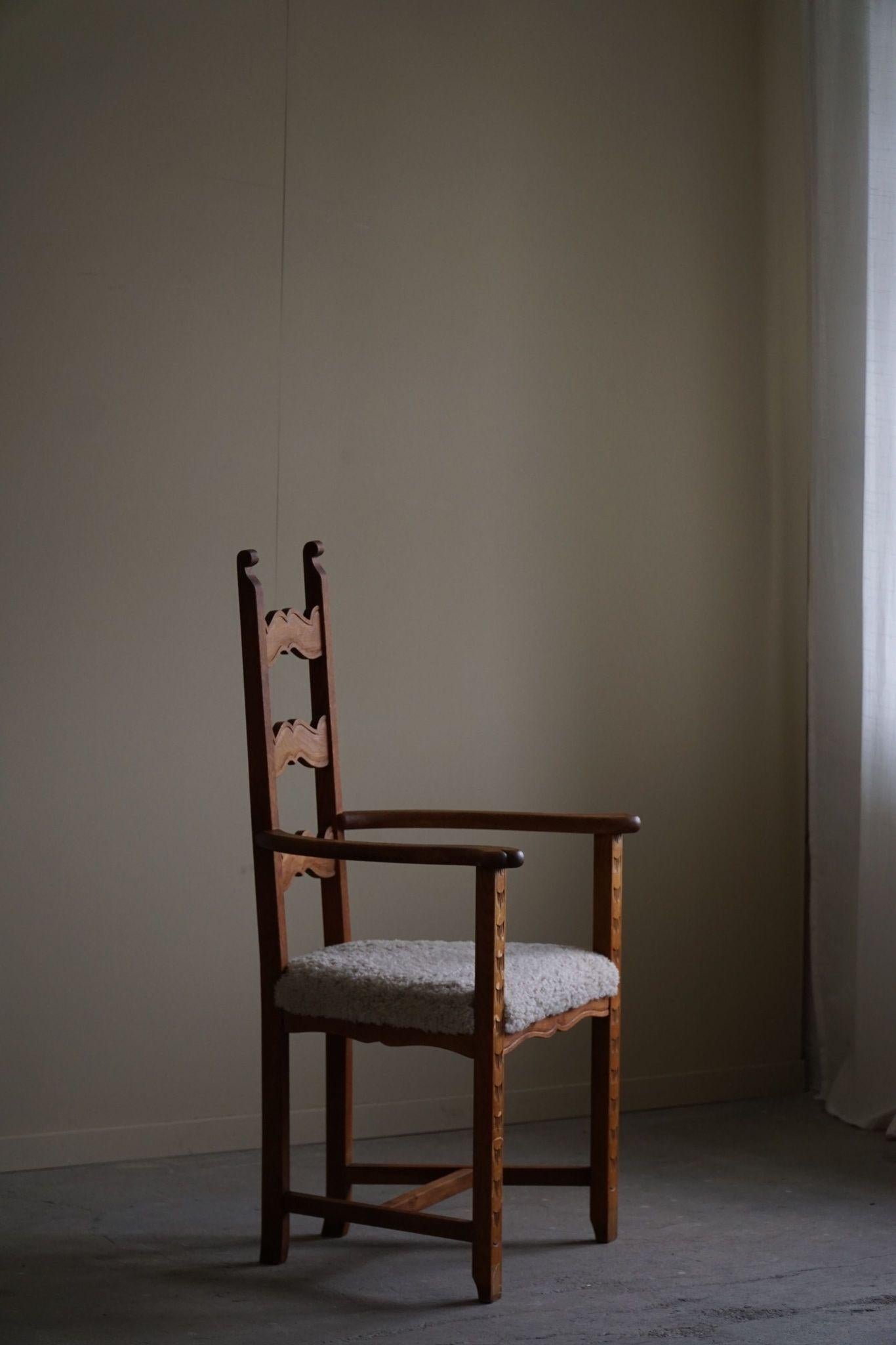 This Danish Mid-Century Modern armchair from the 1950s is crafted from oak with delicate carvings for added detail. The seat is upholstered in soft lambswool, blending comfort with the chair’s clean, classic lines and subtle decorative touches,