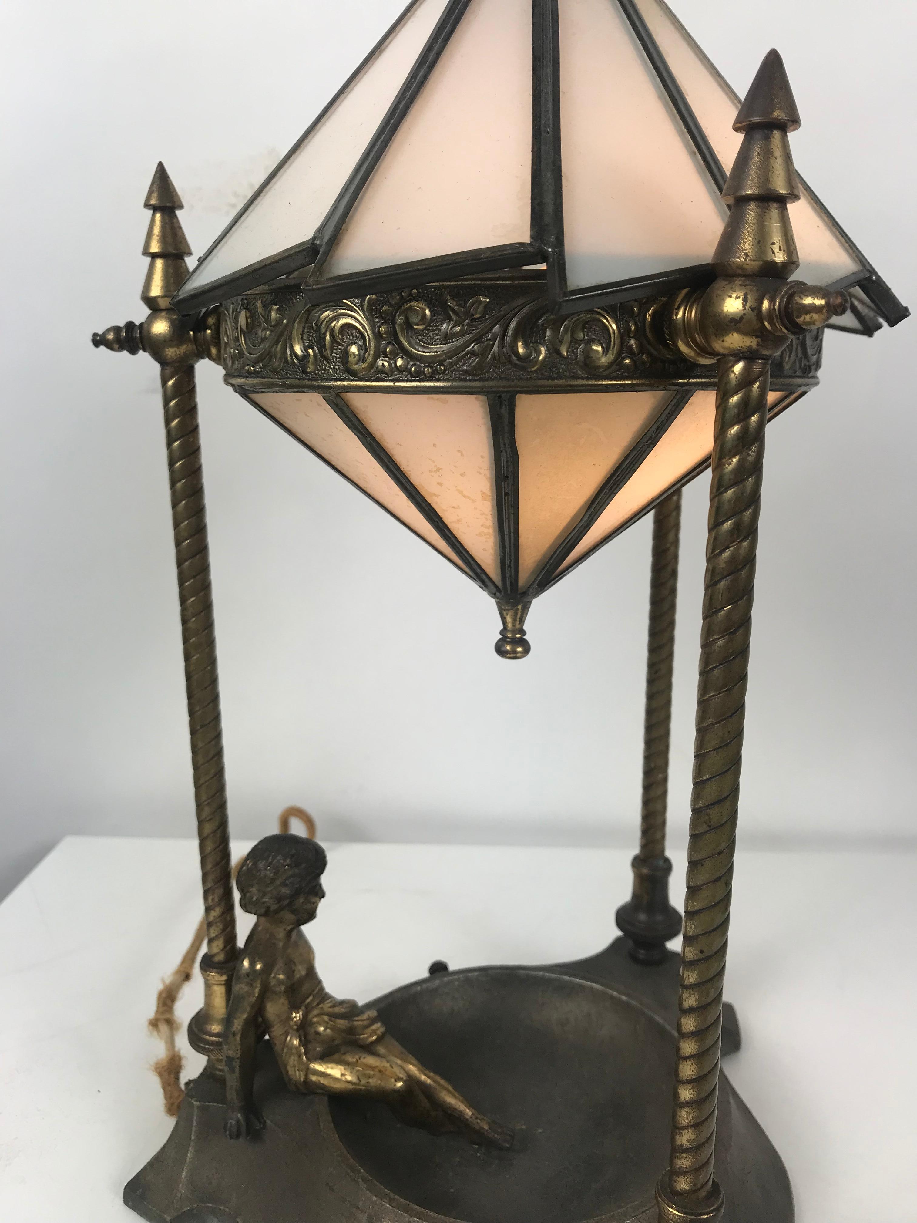 Classic Art Deco Boudoir lamp with stunning ziggurat leaded
slag glass shade, lamp depicting gold gilt sitting angel, super stylized stepped deco finials.