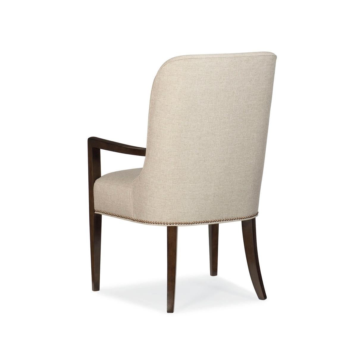Clean, classic lines, fully upholstered in a neutral brushed fabric, its open, squared-off arms and tapered sabre legs are finished in Bourbon Glaze. With its band of brass nails at the base, these chairs pair well with modern and transitional