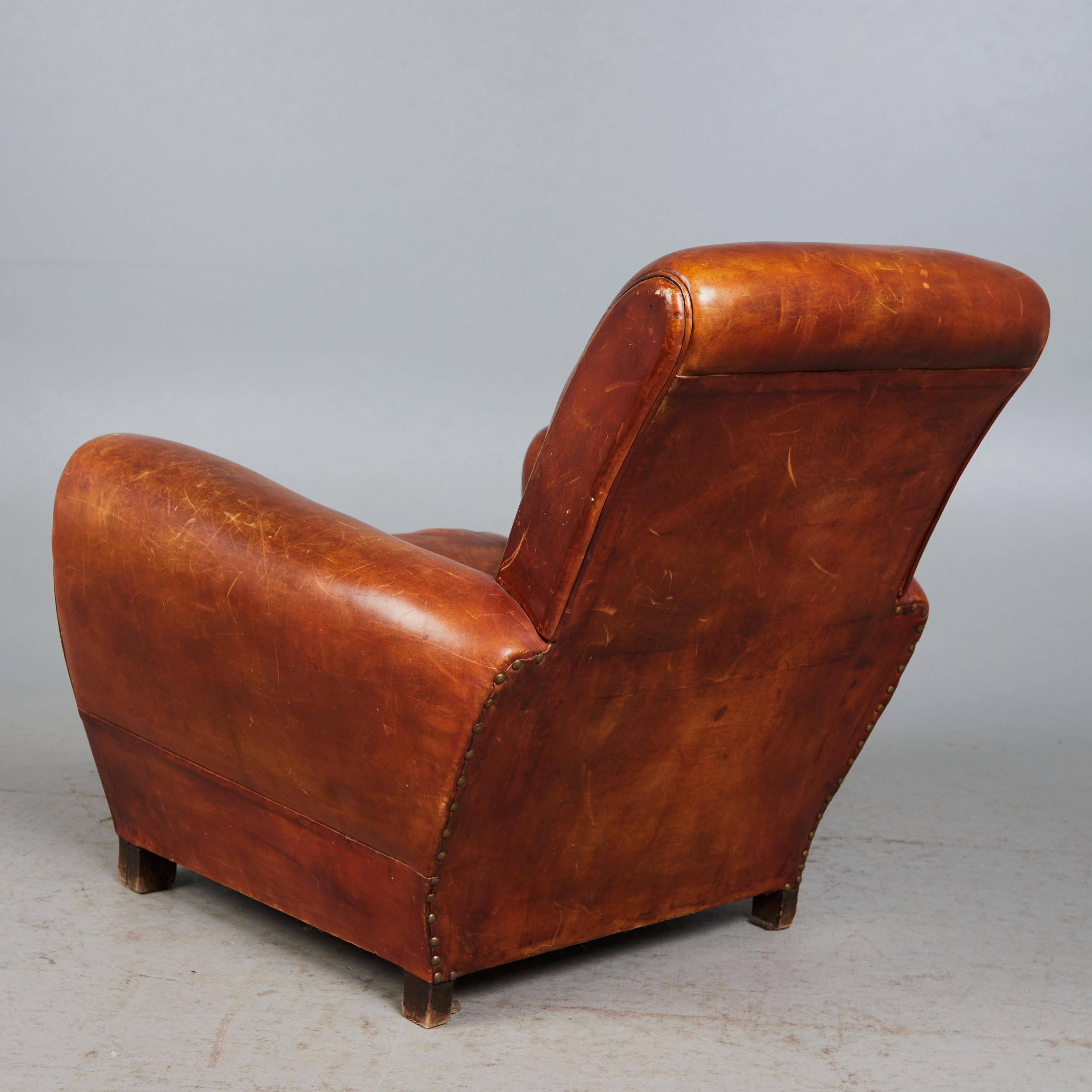 Classic Art Déco leather upholstered brown club chair / Lounge chair . France 1930s. 
Original, good general  condition.
Wooden feet.
Studded trim on the back
Signs of use and age-related wear but in a good condition.
Leather partially