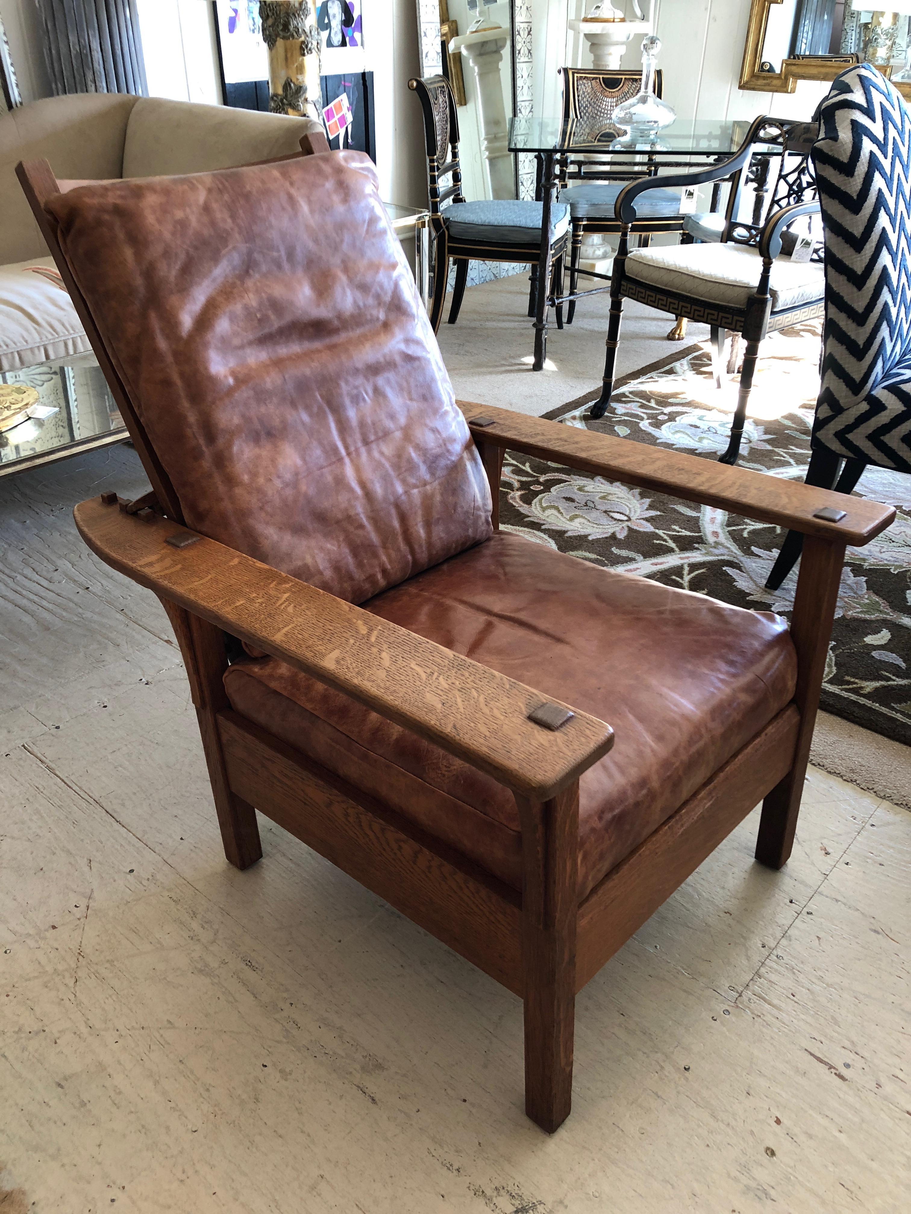 Handsome Arts & Crafts Morris lounge chair having an adjustable back with notched wood system and distressed leather seat and back cushion. 
Measures: Seat depth 21 arm height 23.75.