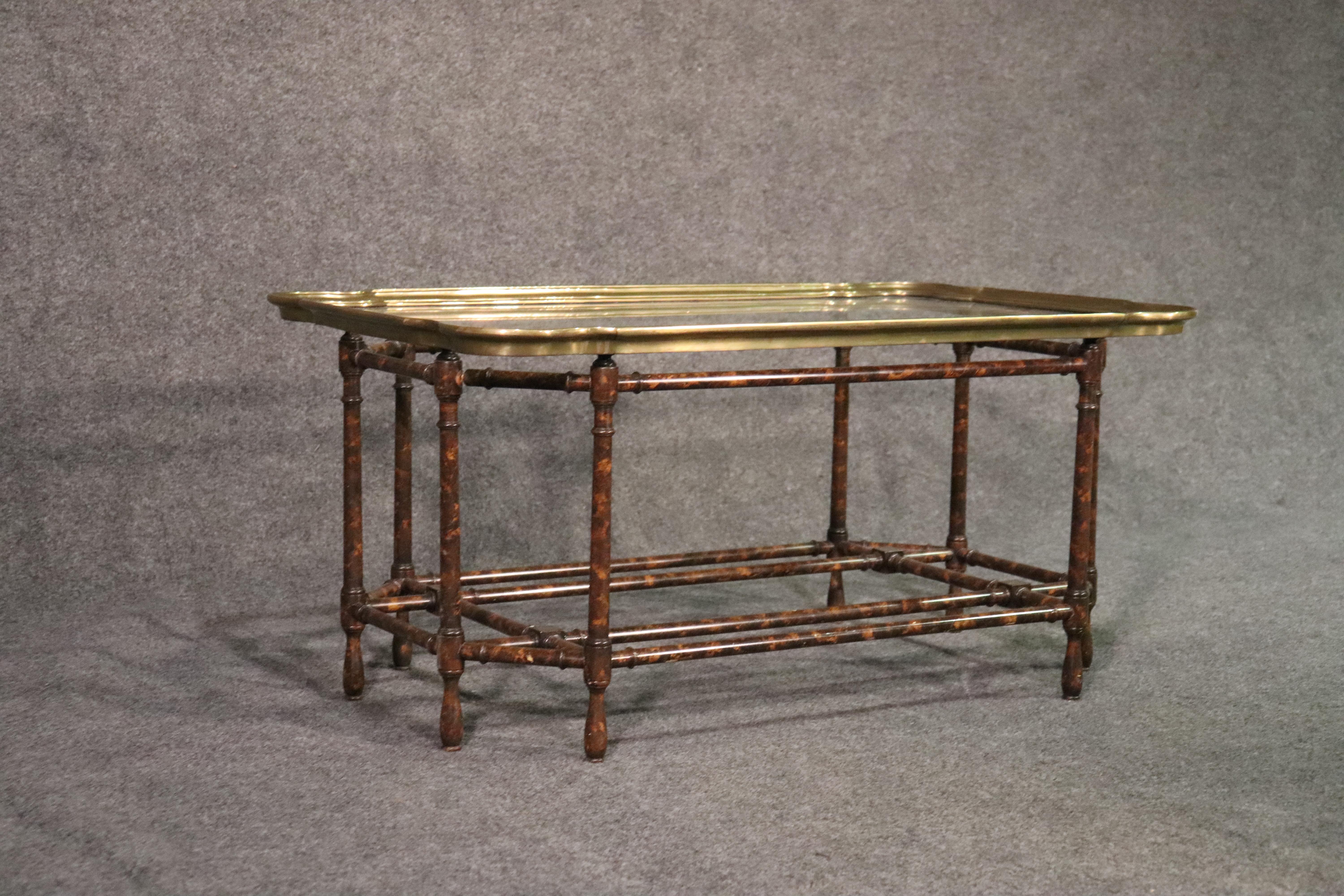 This is a classic brass tray top coffee table. The table is in good condition and has no major issues. The table top has fine scratches from use but nothing serious. The table dates to the 1960s and measures 38 wide x 23.25 deep x 18.25 tall.