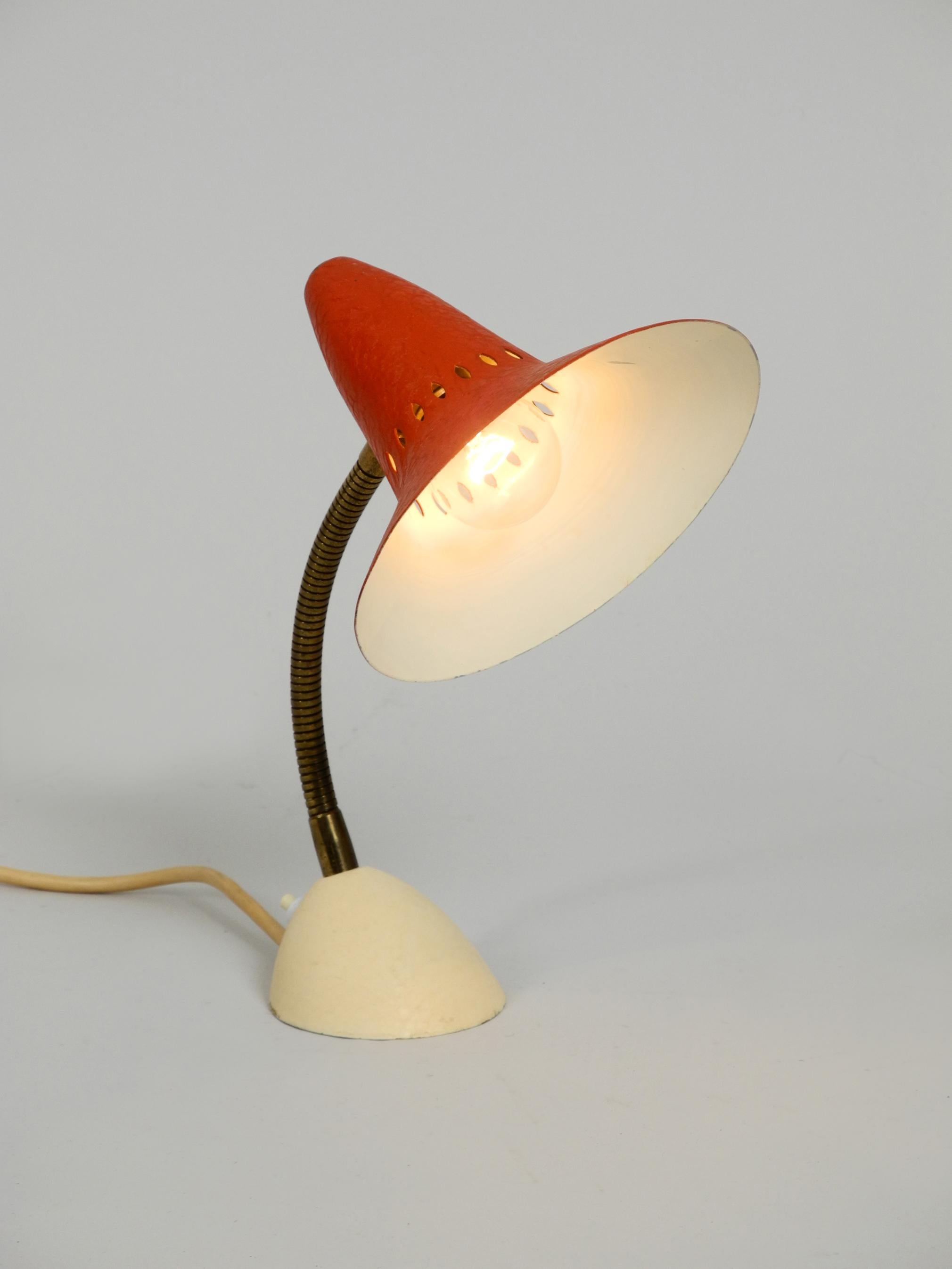 Classic very nice Mid-Century Modern table lamp.
Very nice typical minimalistic midcentury design with a fantastic patina.
Red lacquered aluminum shade with heavy metal base.
The neck is made of flexibly adjustable brass. Holds in every