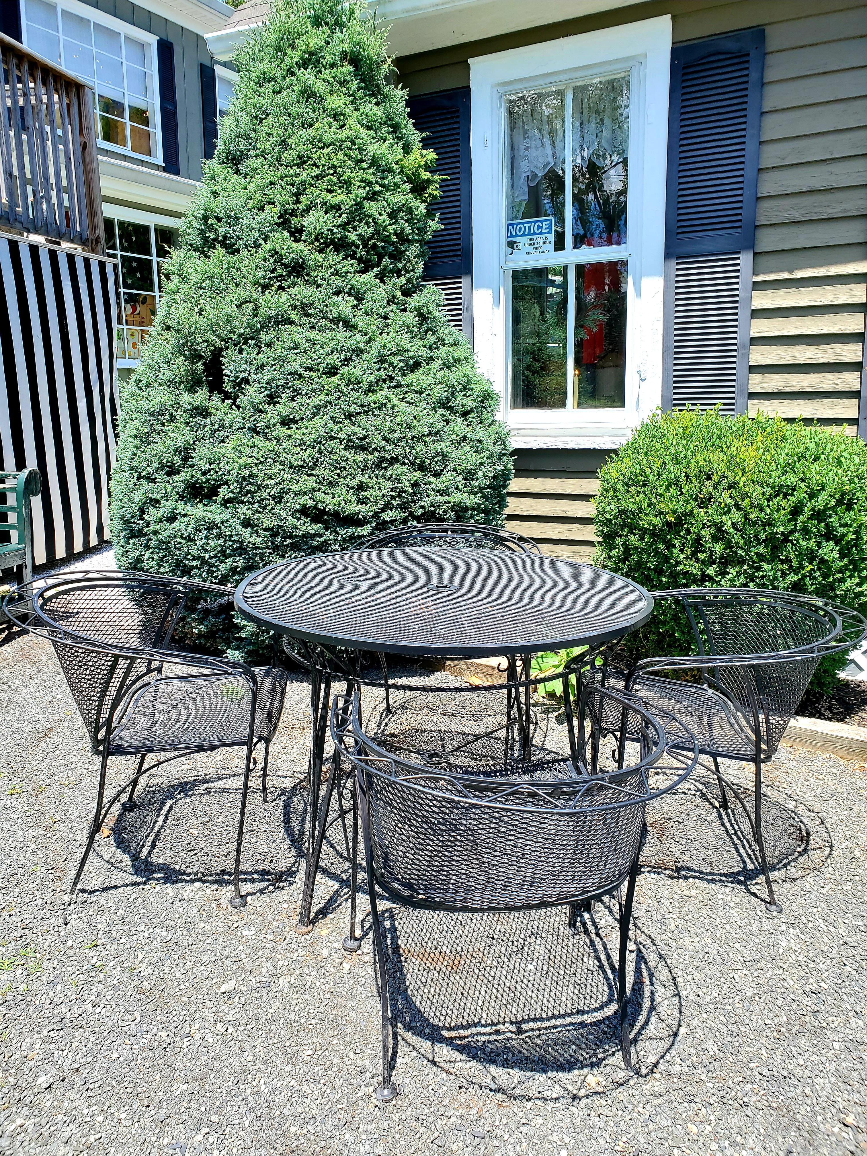 A classically styled 5 piece black iron mid century modern round dining table with 4 matching curvy arm chairs. 
Chairs 26 W, 28 H, 25 D.
