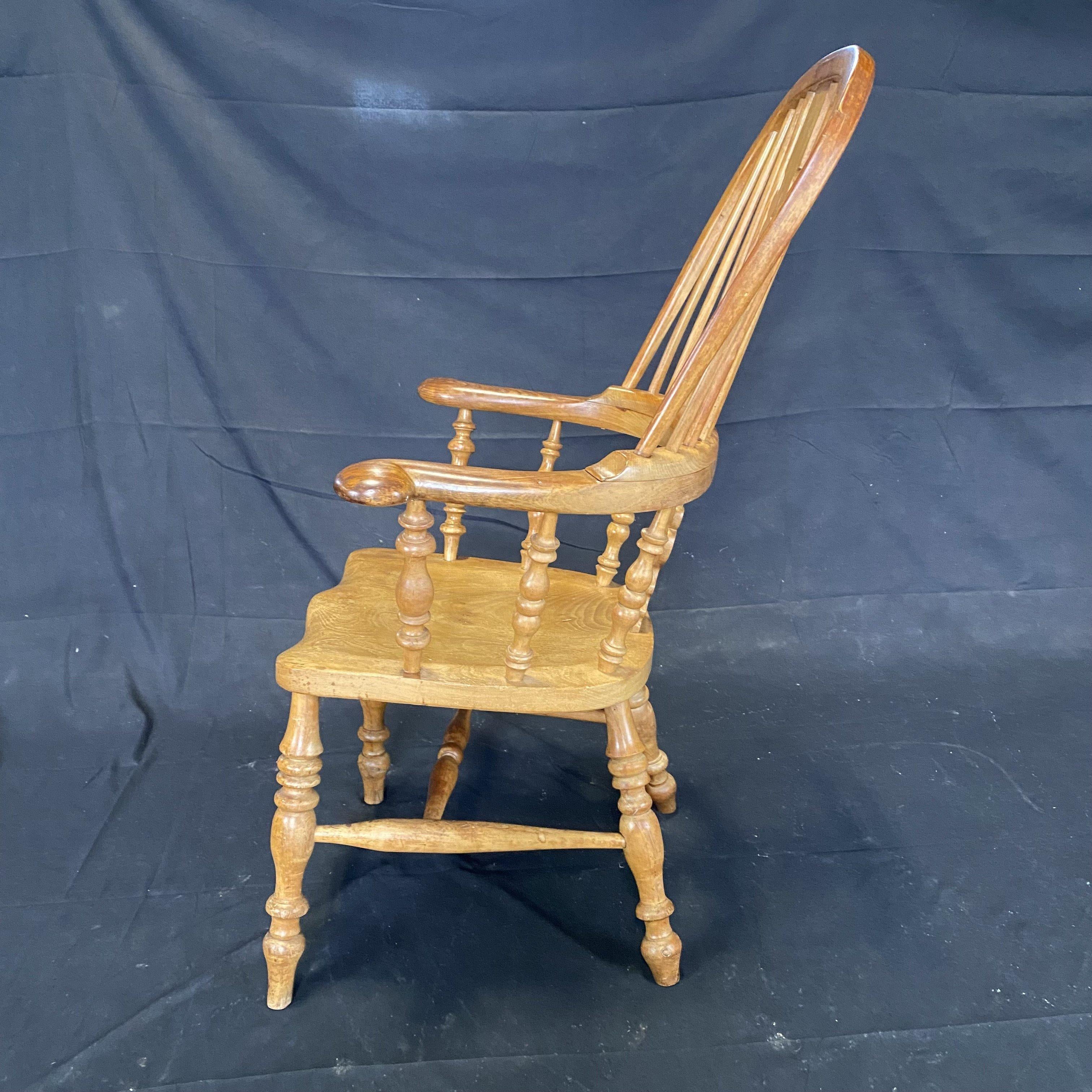 Early 20th century Windsor oak armchair with turned legs and stretcher, well figured and very comfortable. The Windsor chair is established as one of the great classics of English country furniture. Made by village craftsmen to traditional designs