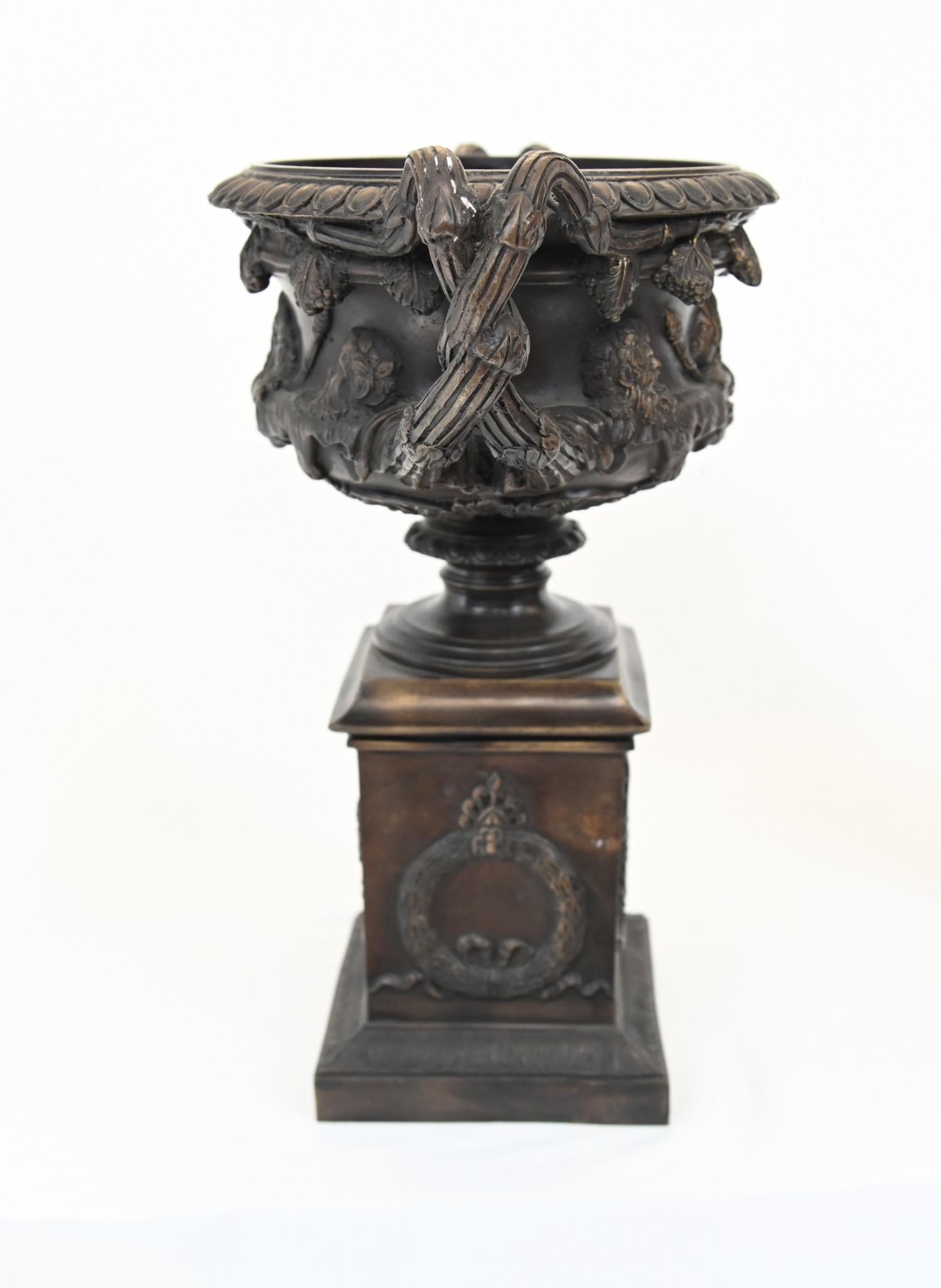 You are viewing a pair of Italian bronze urns of campana form
These are modelled after the famous Warwick vase 
The Warwick Vase is a renowned ancient Roman marble vase, discovered at Hadrian's Villa in Tivoli, Italy. It features elaborate Bacchic