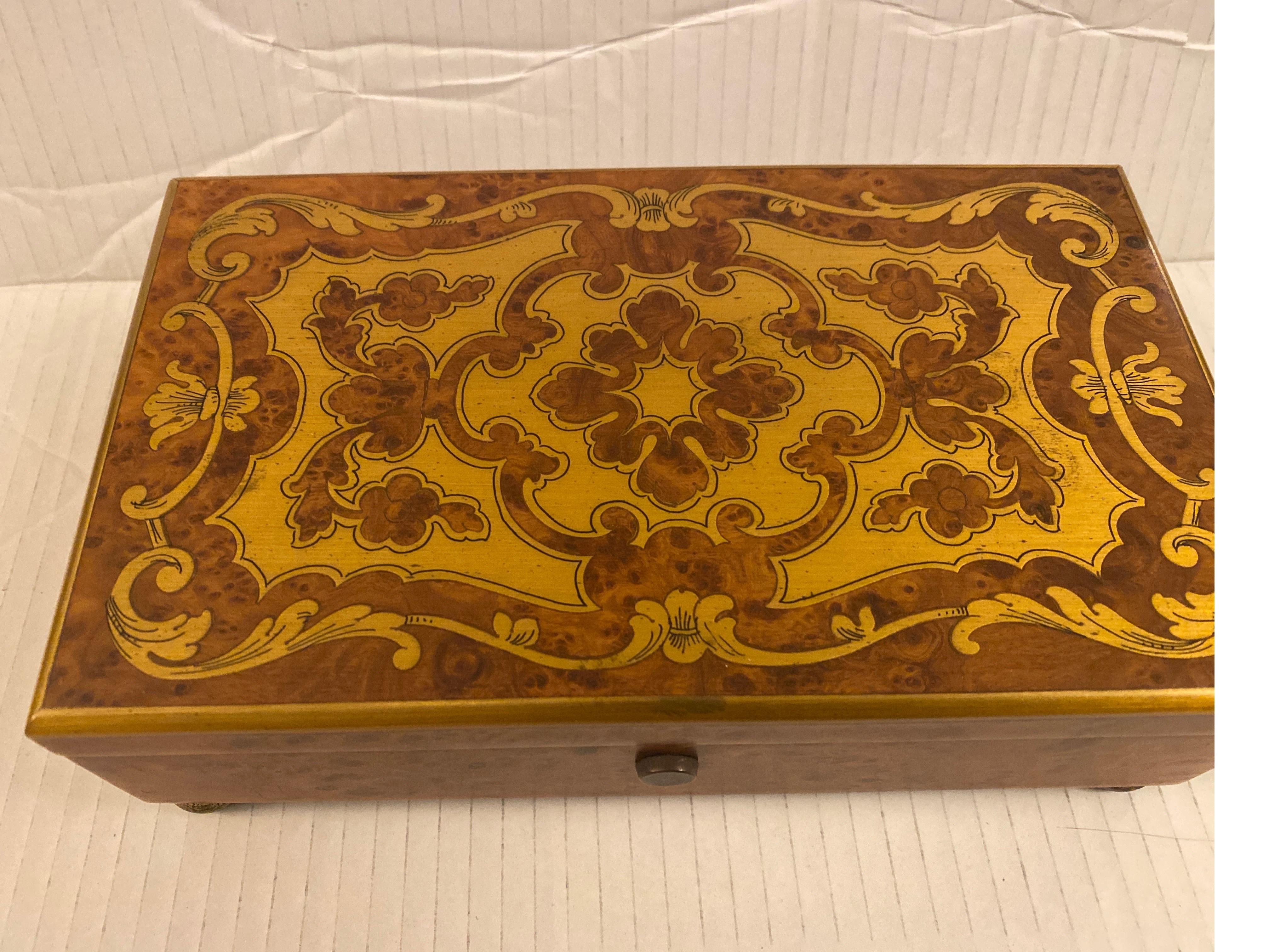 This beautiful burl walnut music box with elegant brass inlaid top plays four different tunes. The rich sound resonated richly and has the workings made in Switzerland. The on and off button at the front will shut off after playing a complete song