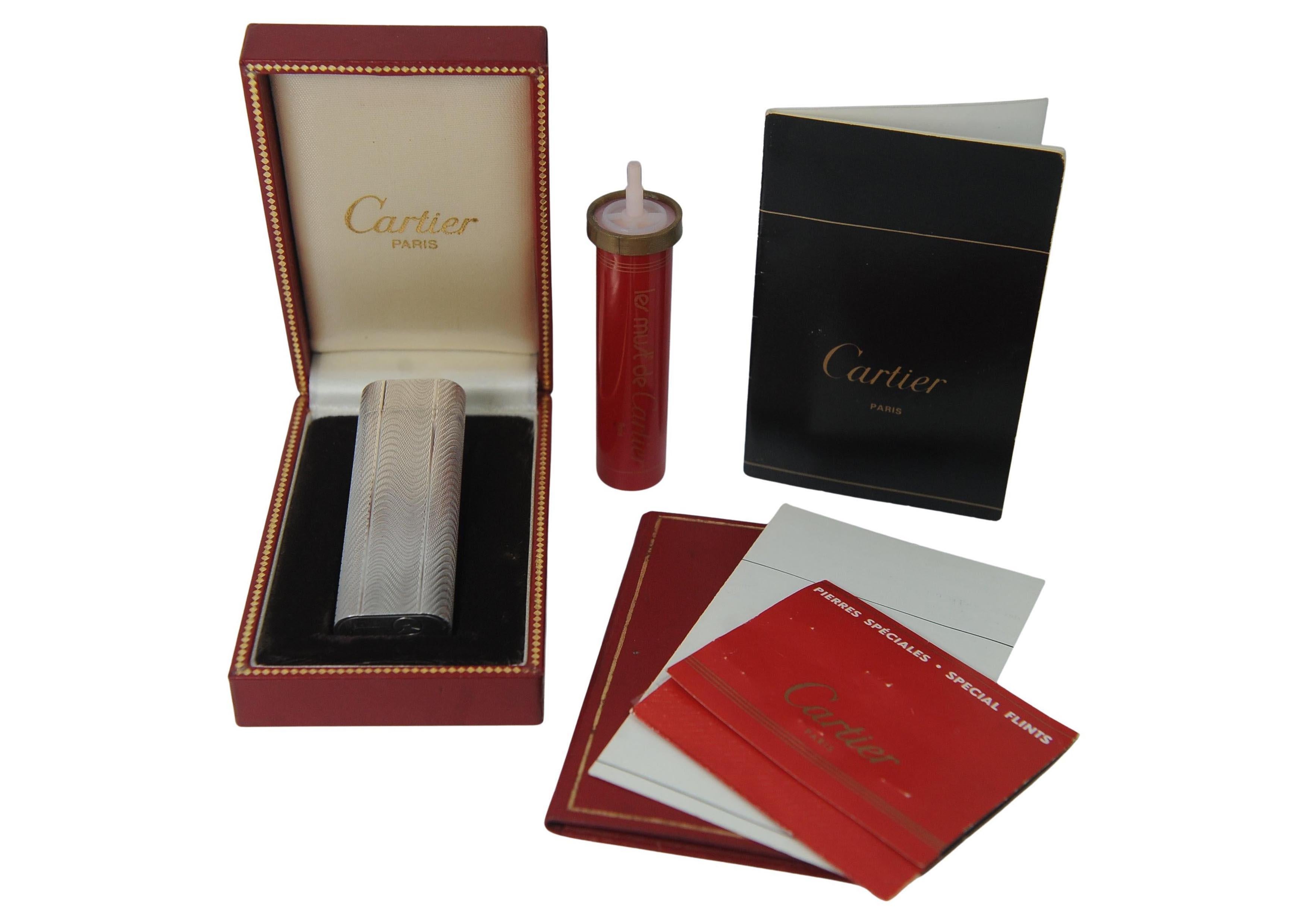Accendisigari classico placcato in argento di Cartier con scatola, pietre focaie e bomboletta del gas e documenti di garanzia originali di Cartier

In ordine e funzionante, Made in Paris, France 

Cartier International SNC, o semplicemente Cartier,