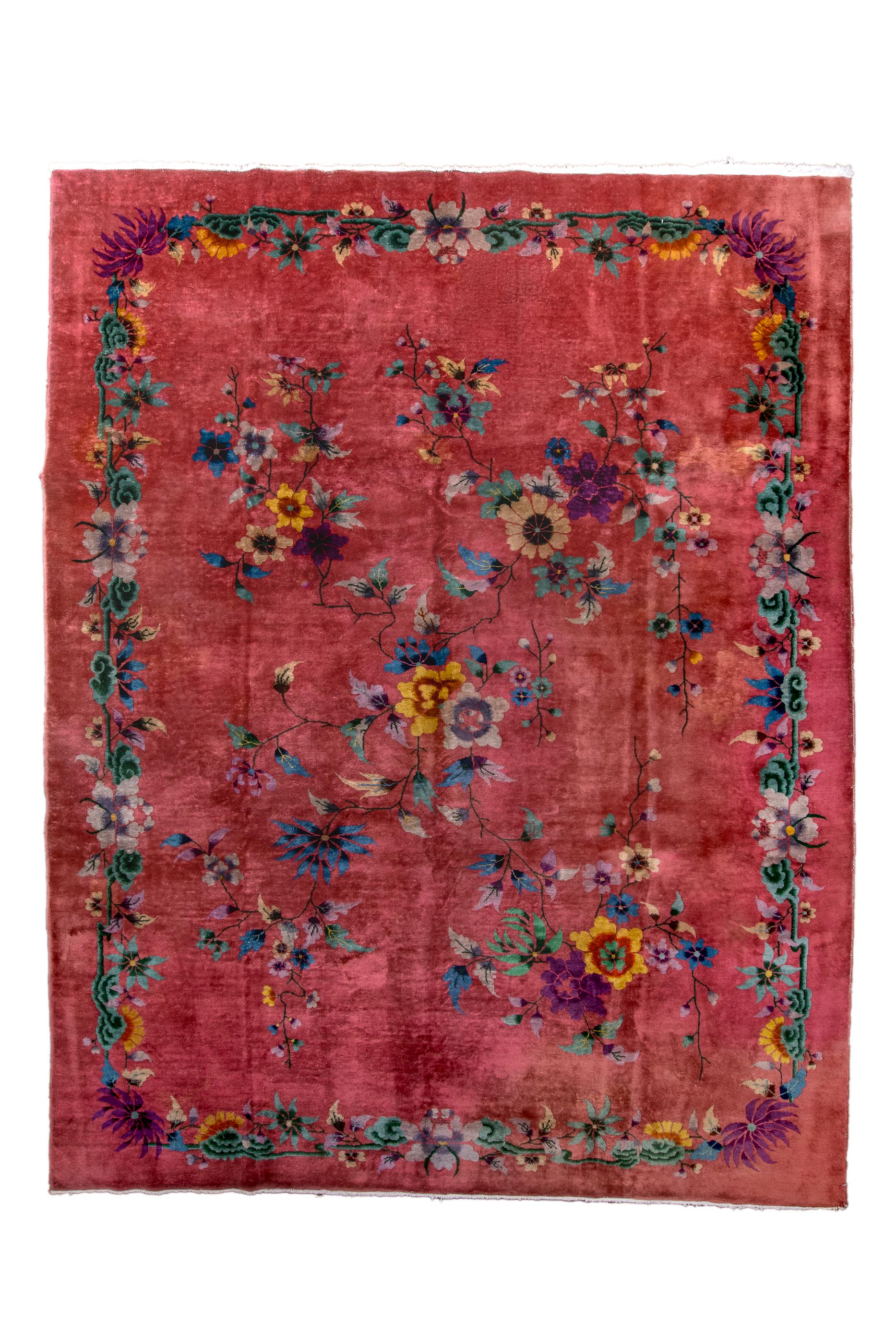 This bold Art Deco carpet from Tianjin (Tientsin) features a rose-tone ground, with an open floral trellis border, and en suite inner floral decorations of blossoms in canary yellow, cerulean blue, pale blue, teal and green, on black, wiry stalks. 