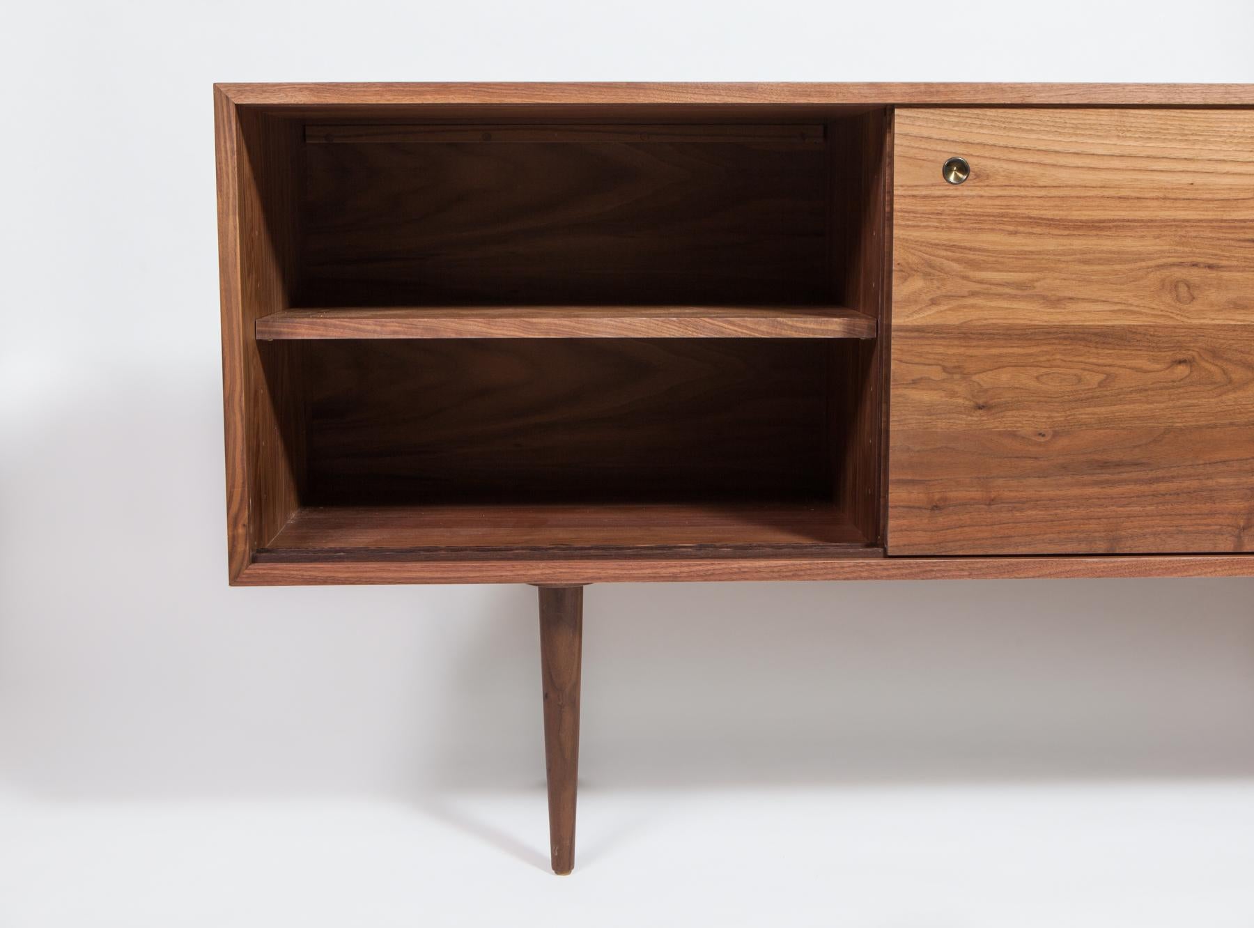 Originally designed by Mel Smilow in 1950 and officially reintroduced by his daughter Judy Smilow in 2013, the solid walnut Credenza with matching doors has a beautifully finished front and back. The focal point of any Mid-Century Modern home, its
