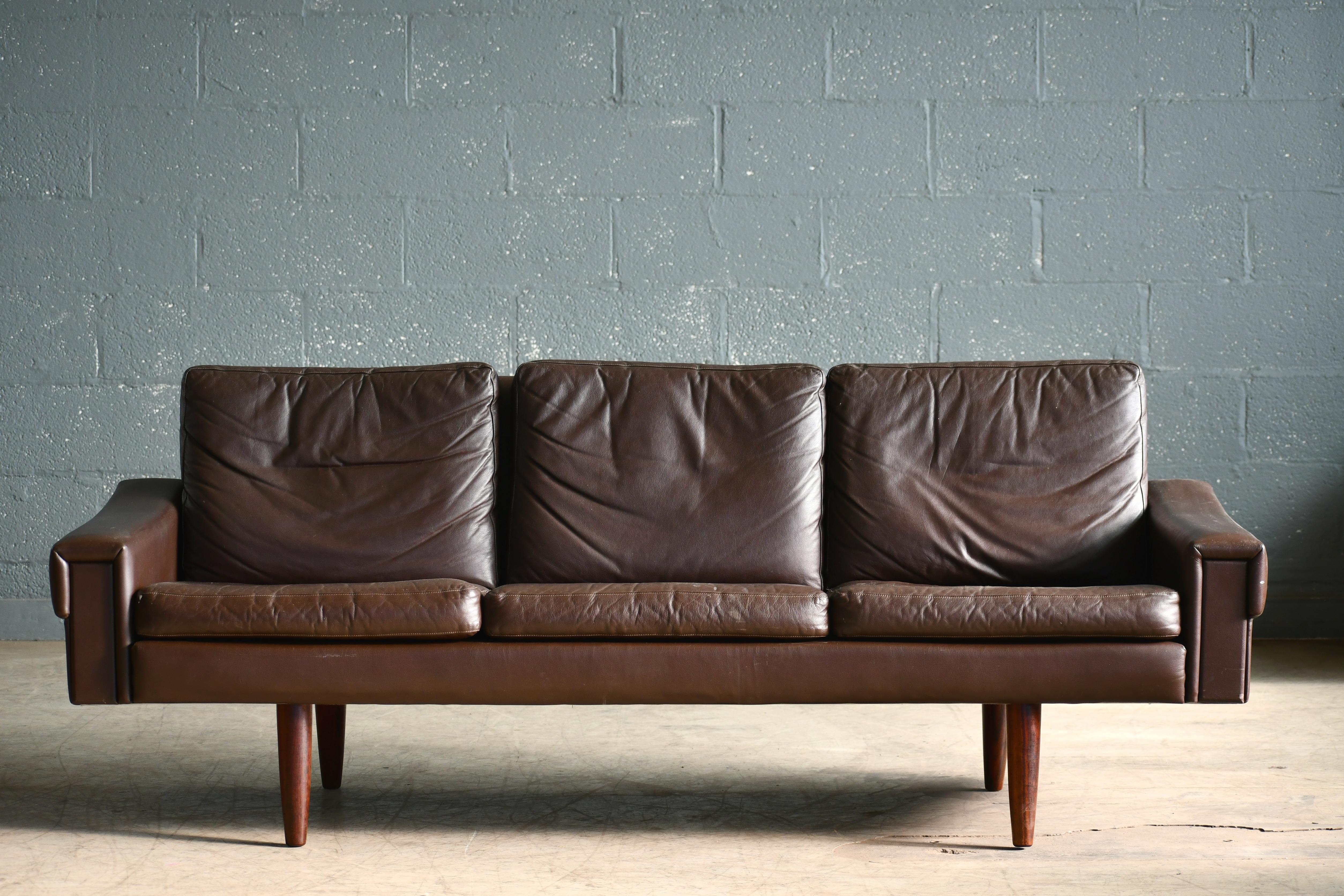 Classic Danish midcentury three-seat leather sofa in a nice warm chestnut color designed by Georg Thams in the 1960s and manufactured by Vejen Polstermobelfabrik in Denmark. Very elegant yes relaxed with leather inserts on the front of the armrests