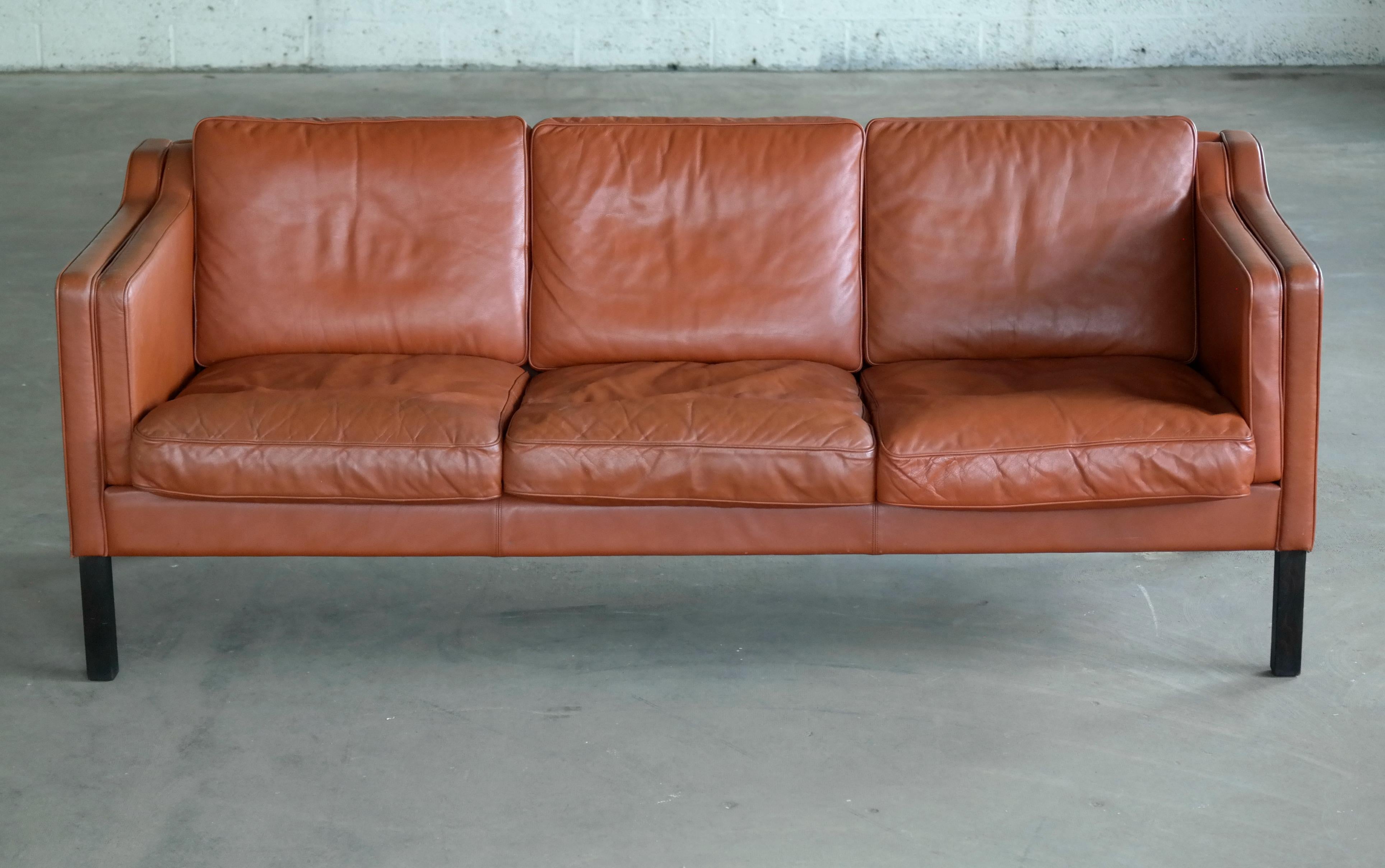 Classic three-seat sofa similar to Børge Mogensen's model 2213 in a great warm cognac tone of leather with legs in rosewood stained beech wood. One of the iconic, elegant and enduring designs coming out of Denmark in the 1960s. Originally designed
