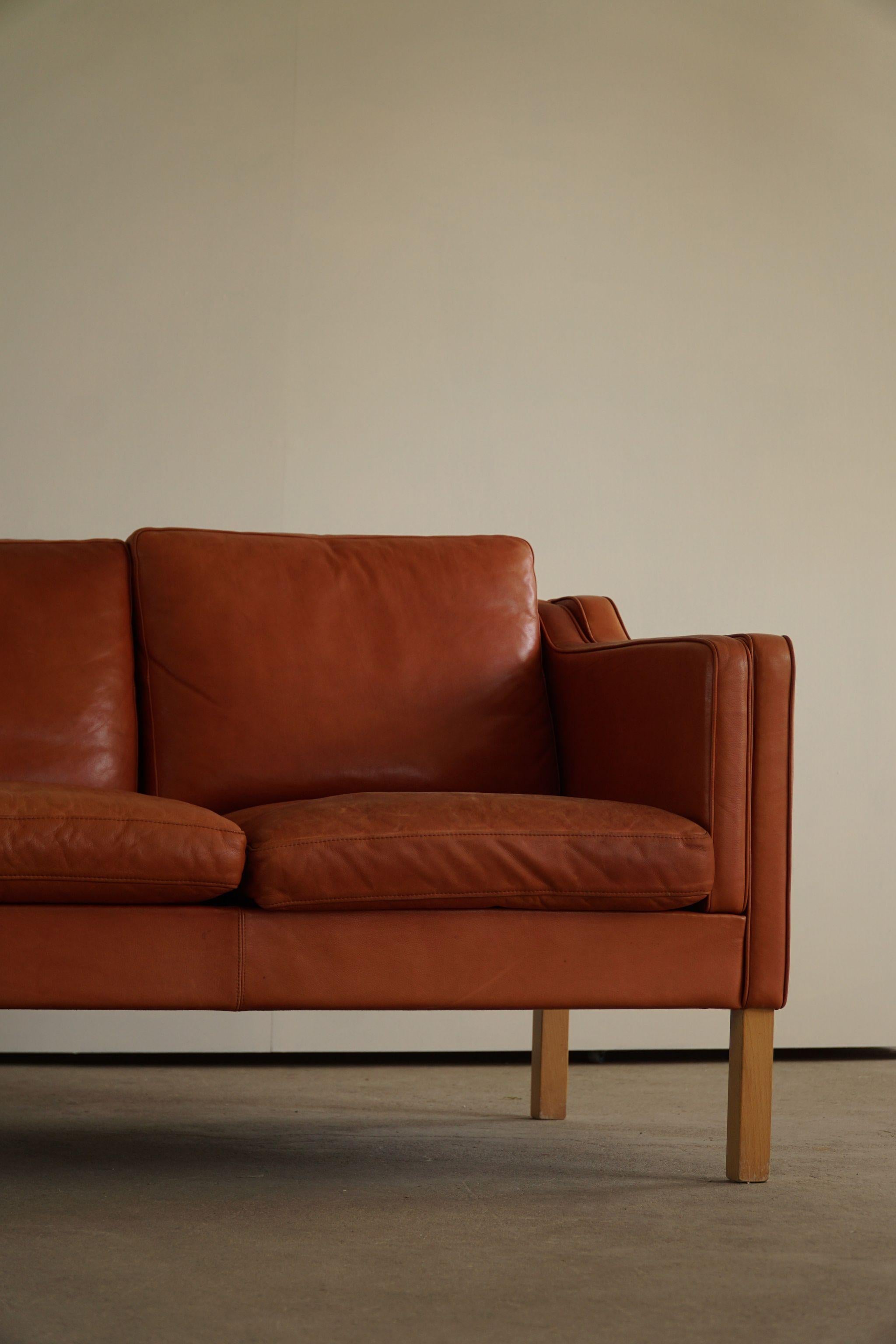 A classic Danish Mordern 3-seater sofa in cognac coloured leather, feets made in solid beech. Simple lines and a great warm patina featured in this sofa. 

With a heavy focus on functionality, this design style leans toward modernism, while