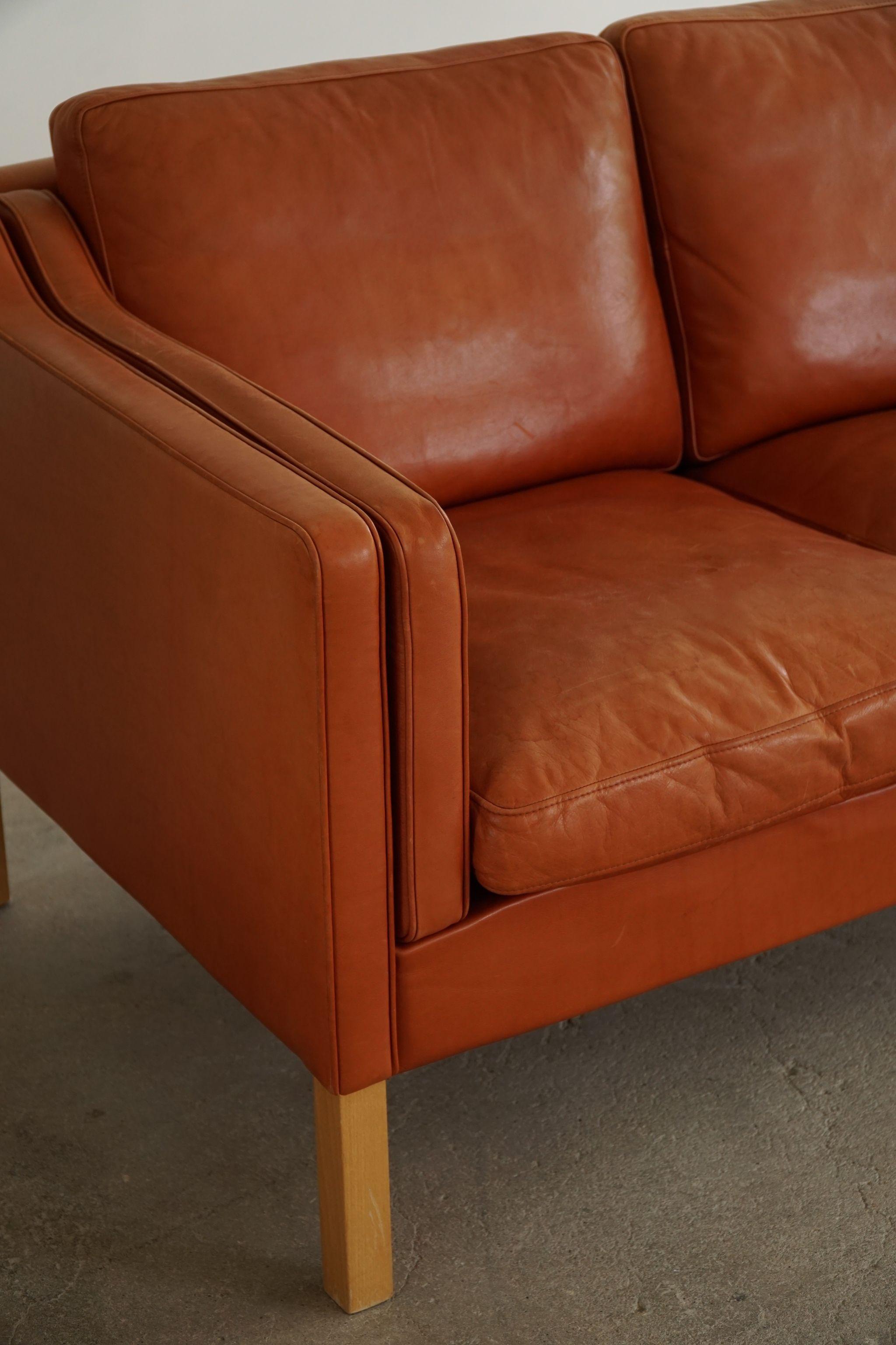A classic Danish Mordern 2-seater sofa in cognac coloured leather, feets made in solid beech. Simple lines and a great warm patina featured in this sofa. 

With a heavy focus on functionality, this design style leans toward modernism, while