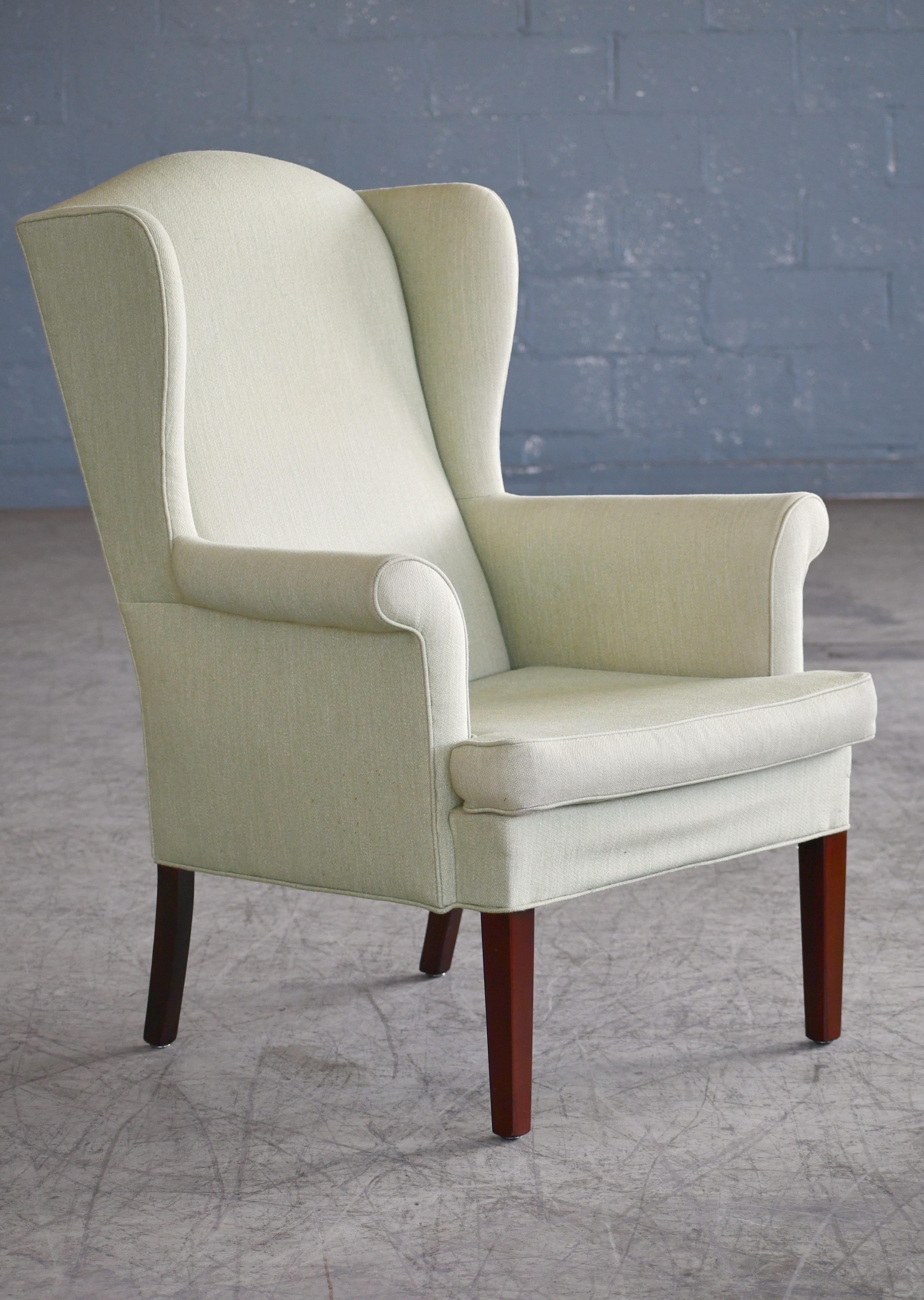 Classic 1950s Danish wingback chair in a nice light green wool fabric raised on mahogany legs. A high quality, comfortable lounge chair. Very refined lines and designed with high attention to detail with clear design cues from the likes of Fritz