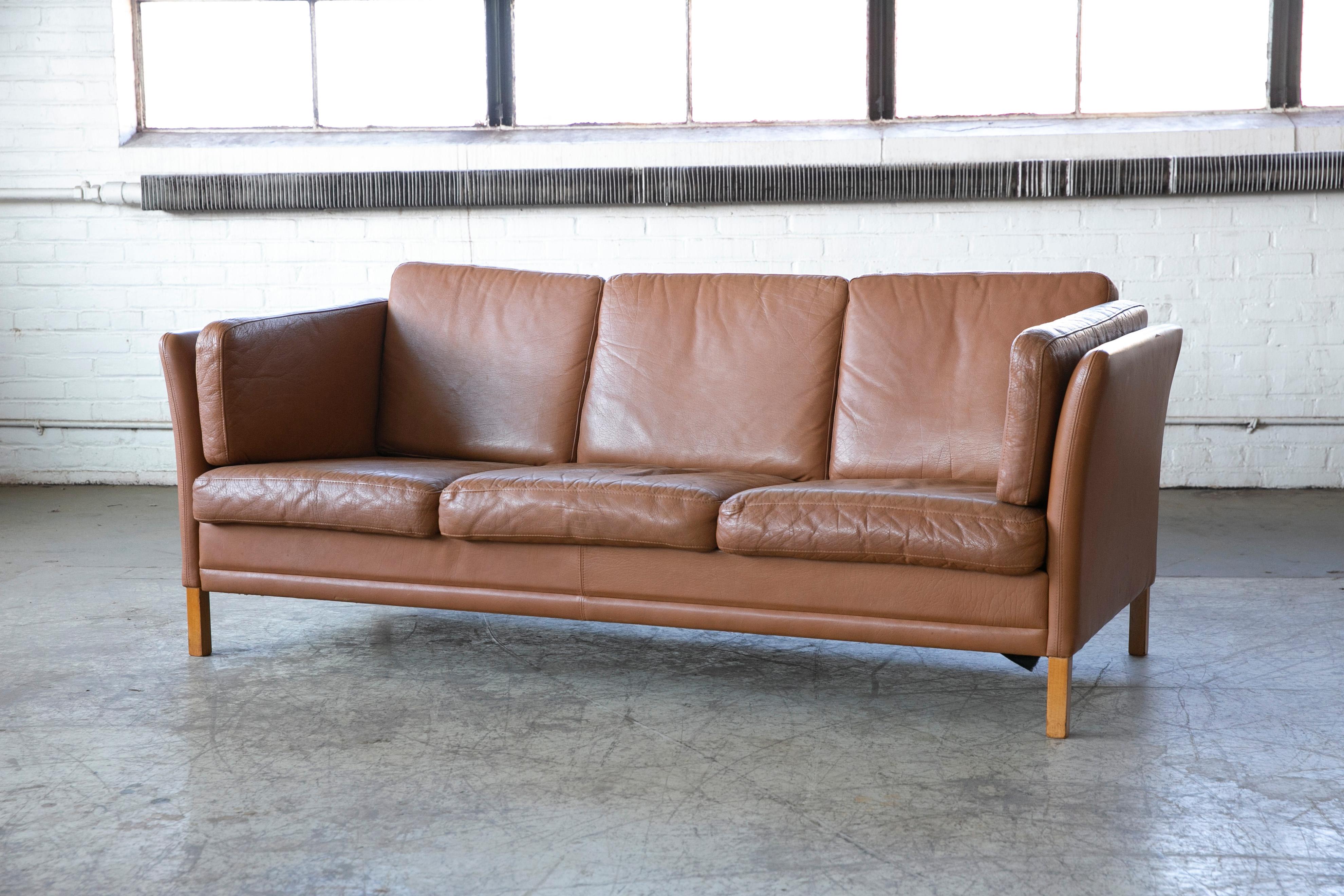 Classic Danish midcentury three-seat leather sofa in a nice warm chestnut color designed by Mogens Hansen - designed in the early 1970s and manufactured by Mogens Hansen's factory in Denmark. Very elegant with the slightly splayed sides and