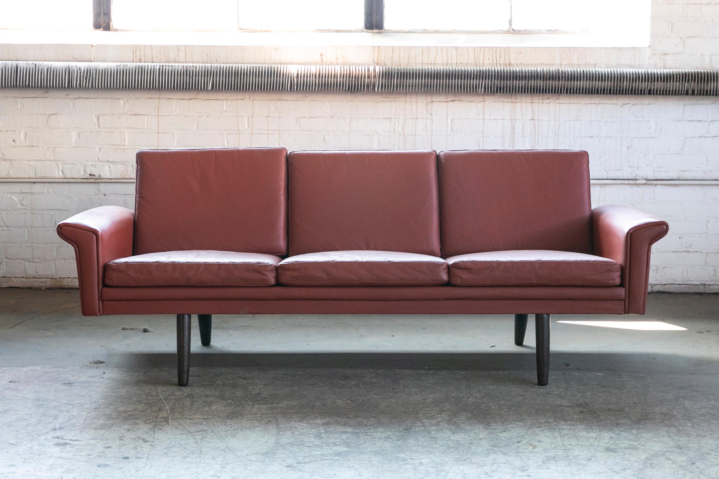 Classic Danish mid-century three-seat leather sofa in a nice warm chestnut color designed by Georg Thams in the late 1960s and manufactured by Vejen Polstermobelfabrik in Denmark. Very elegant with rolled armrests that almost reach out like small