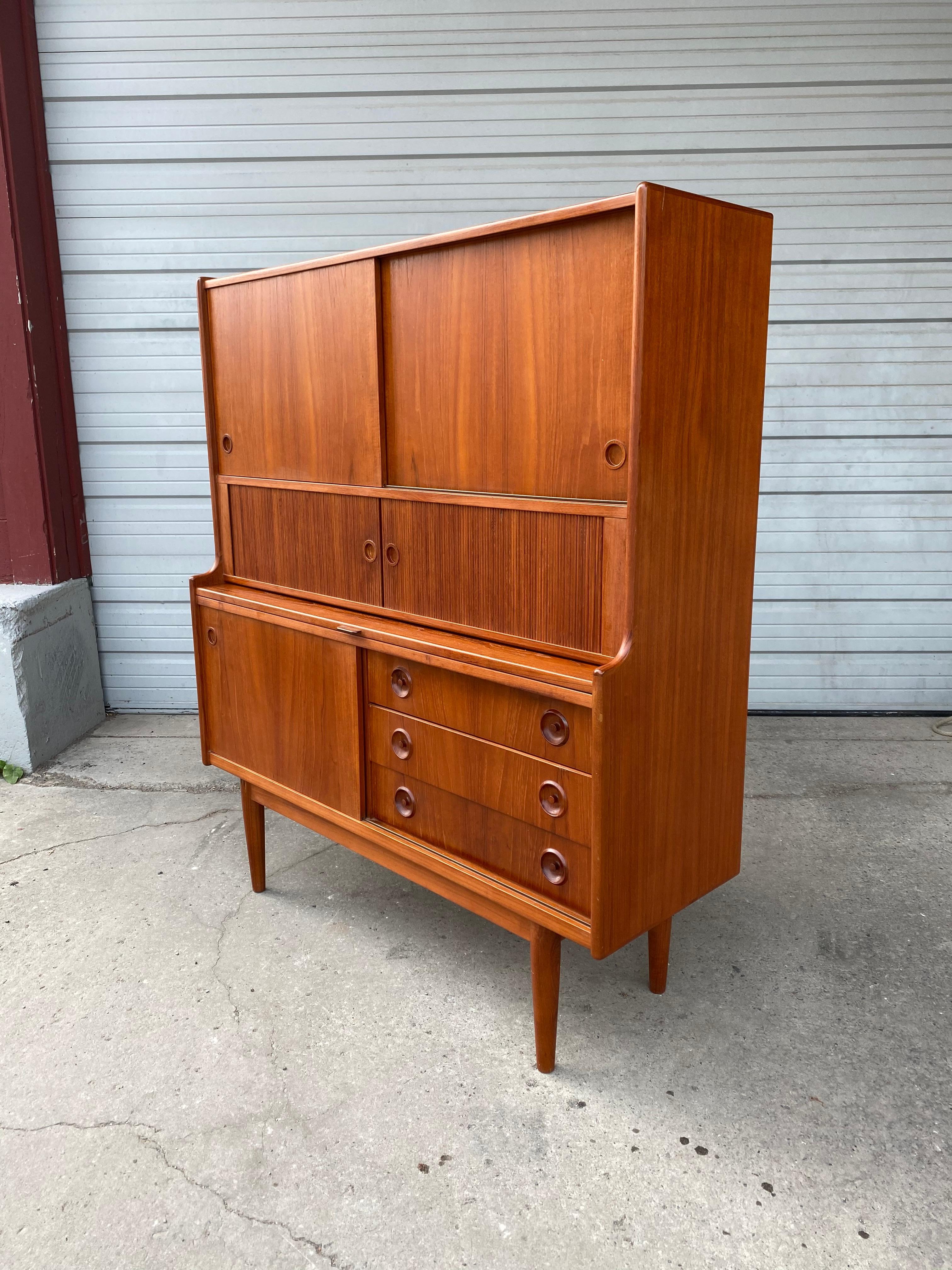 Classic Danish modern teak cabinet or server by Johannes Sorth for Bornholms, made in Denmark, featuring generous storage, tambour doors, drawers, pull out serving shelf, Superior quality and construction, dove-tail joinery, original warm teak wood