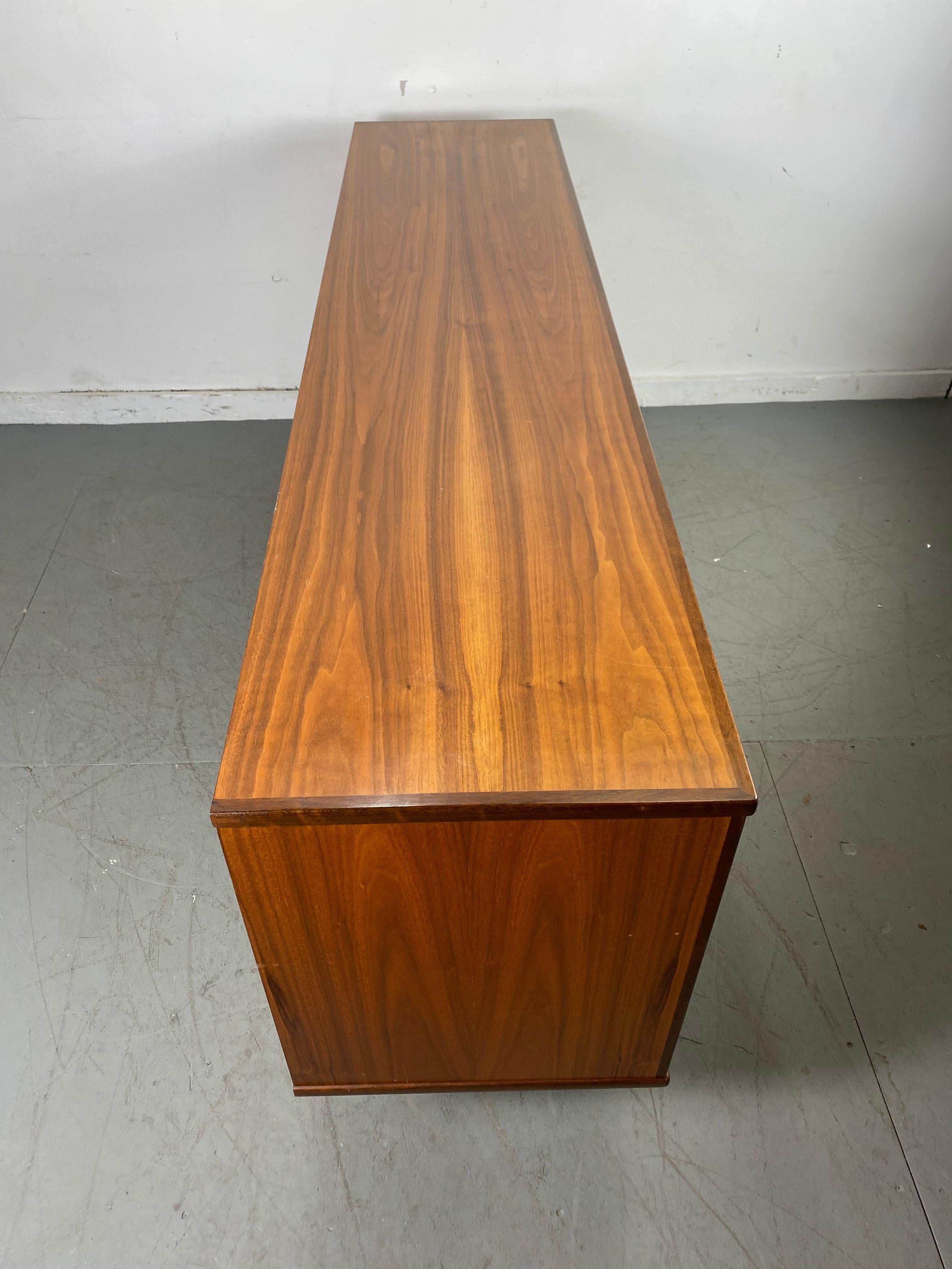 Classic Danish modern teak credenza or sideboard. Stunning grained book-match wood, featuring 3 sliding doors, right side, two dove tail drawers and shelf.