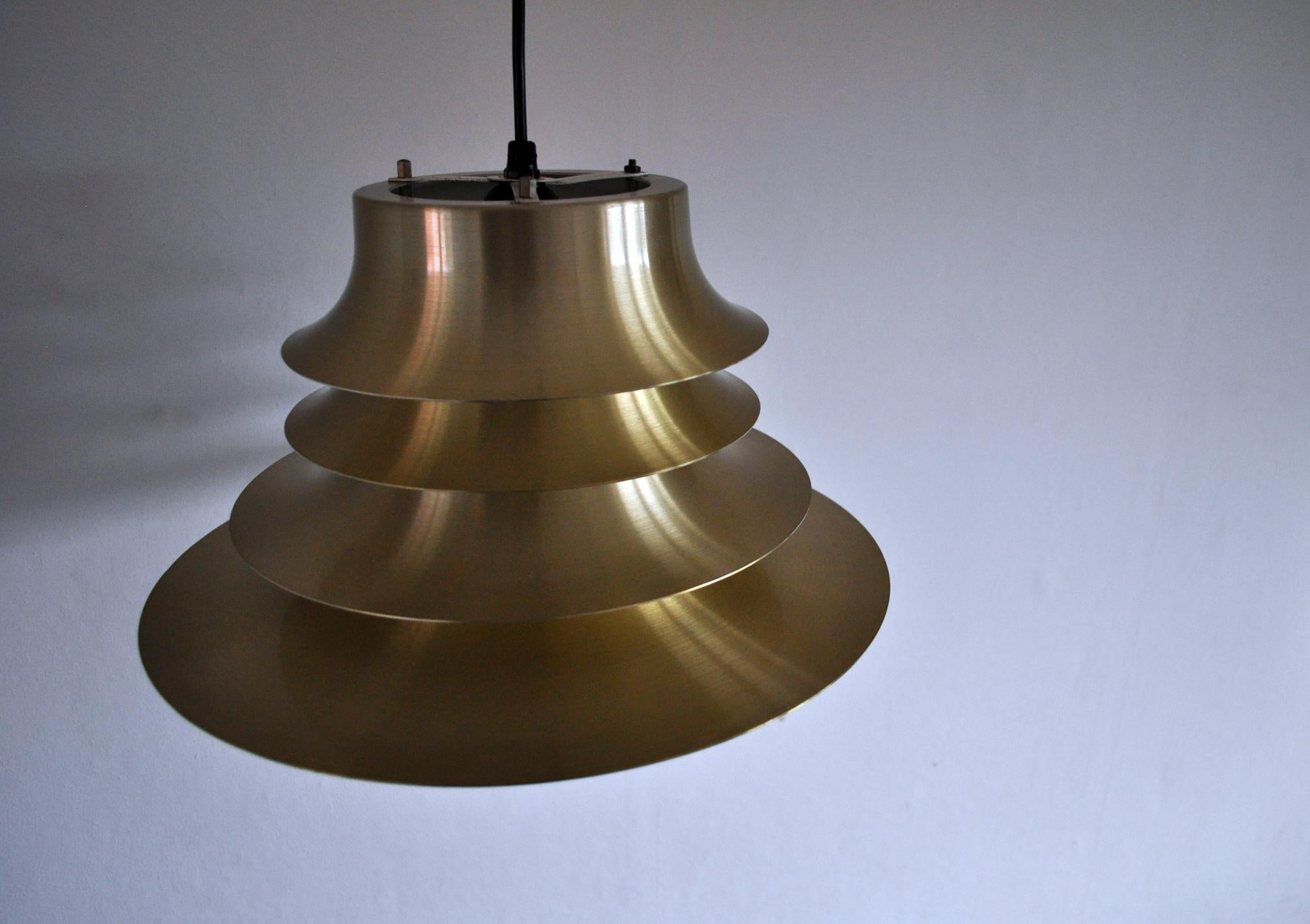 A classic Danish multilayered pendant light in brass with a white enameled inner surface.
Measures: Diameter 35 cm, height 18 cm.
Fine vintage condition.