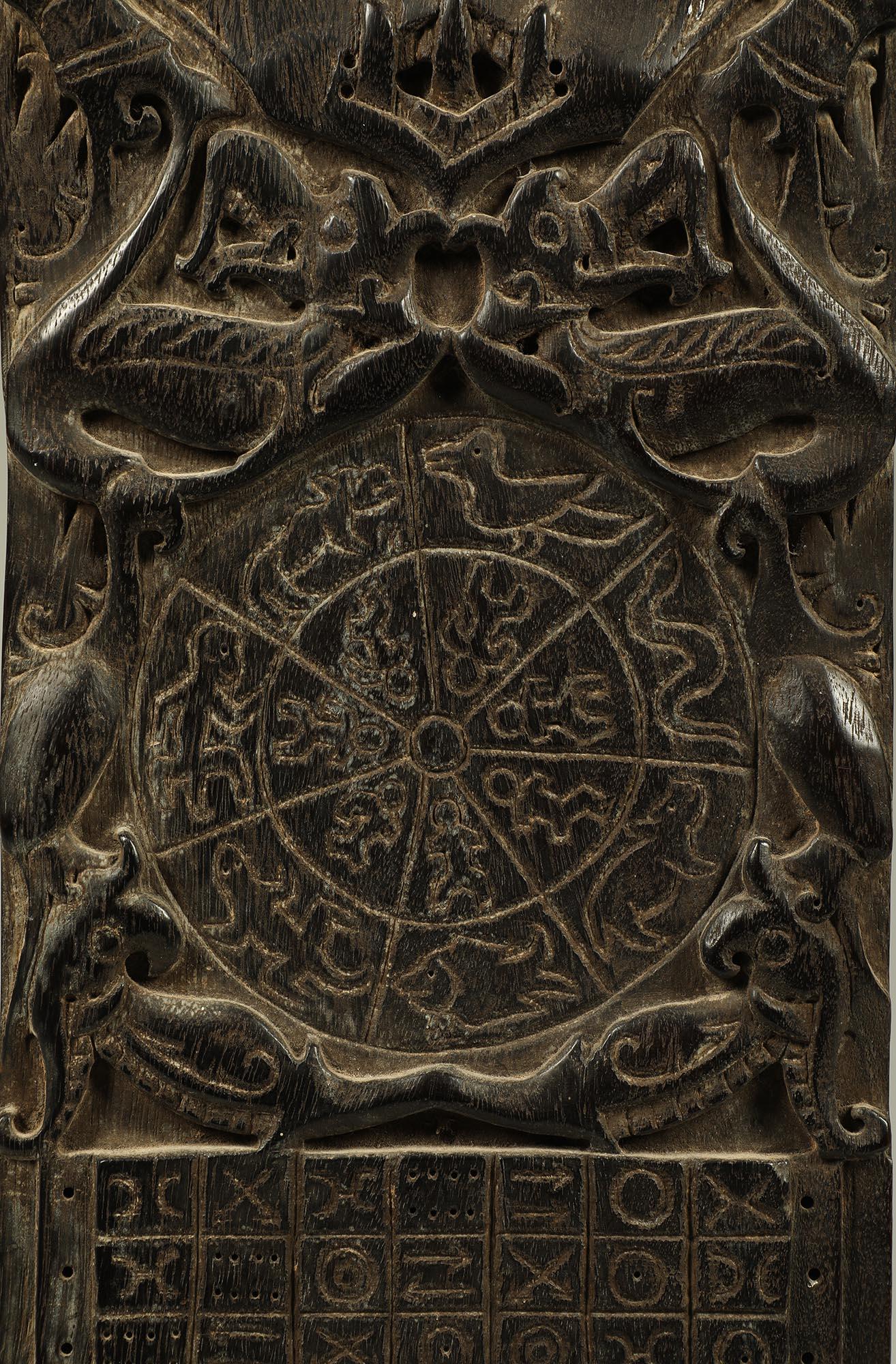 Classic Dayak carved wood calendar board with Aso or Dragon Motifs, Borneo, Indonesia. Traditional very dark wood with carving in relief and incised numbers/calendar marks, and a flat back. 
ex- CA collection, 
18 1/2 inches high, on custom metal