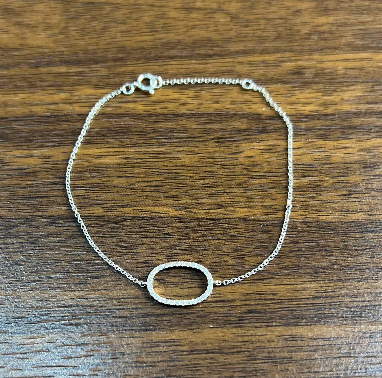 0.19 CTW G/VS Quality White Diamonds. This elegant bracelet features a delicate chain design, crafted with precision. The centerpiece is an oval-shaped openwork element, encrusted with shimmering diamonds that catch the light beautifully. The chain