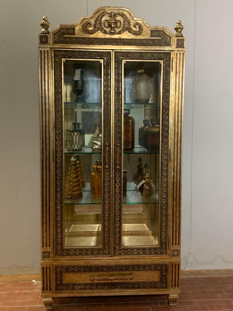 An important Louis XVI style display case revisited in an eclectic manner by O.L.F designs for Lam Lee Group of Dallas. The gold finish is sponge-patinated, creating reddish haloes that stand out against the details and burnished hardware,