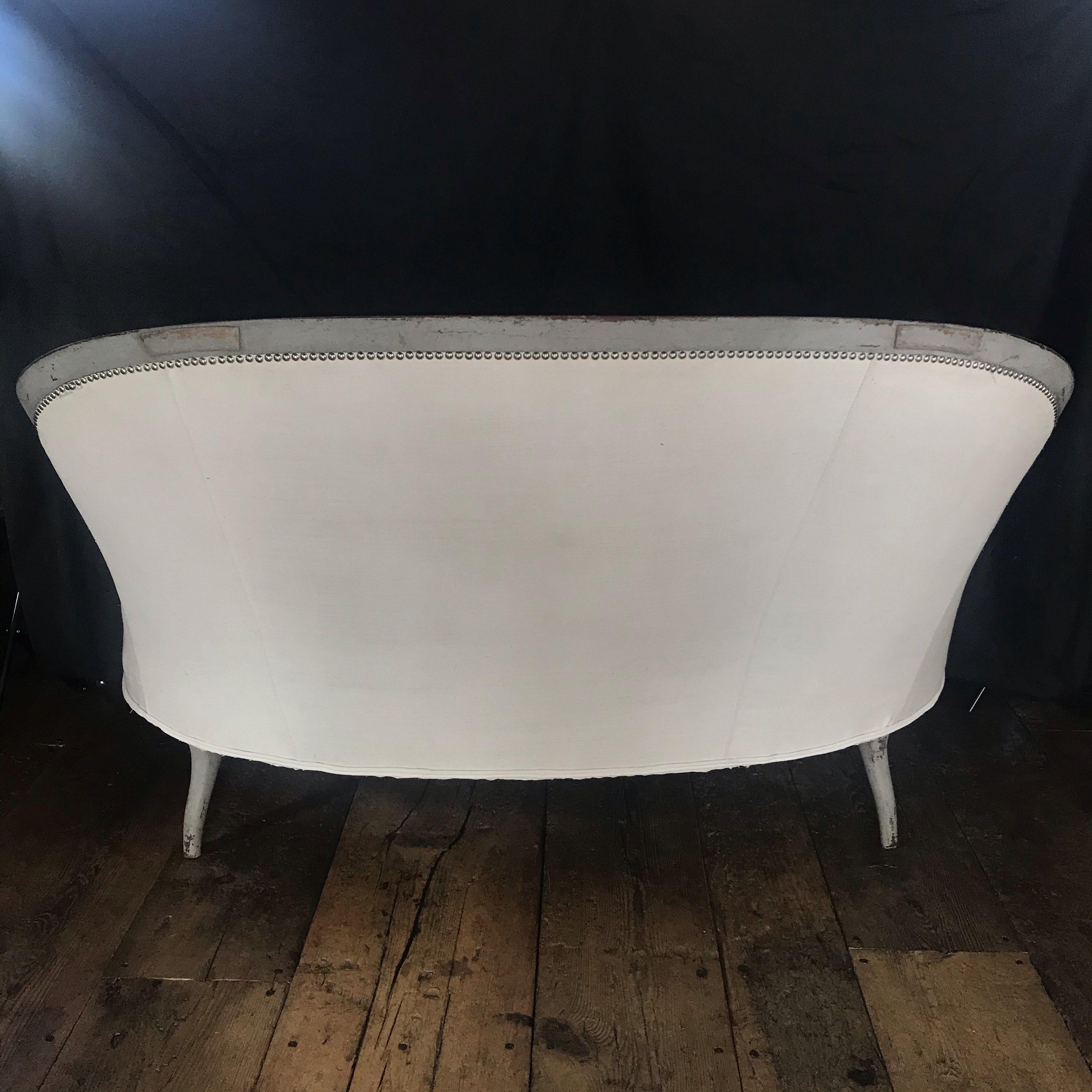 A very elegant and wonderfully drawn French 19th century loveseat small sofa in soft gray paintwork. French, circa 1870. Having a very chic profile, the shapely curved back is decorated with original tacks and reupholstered in immaculate French