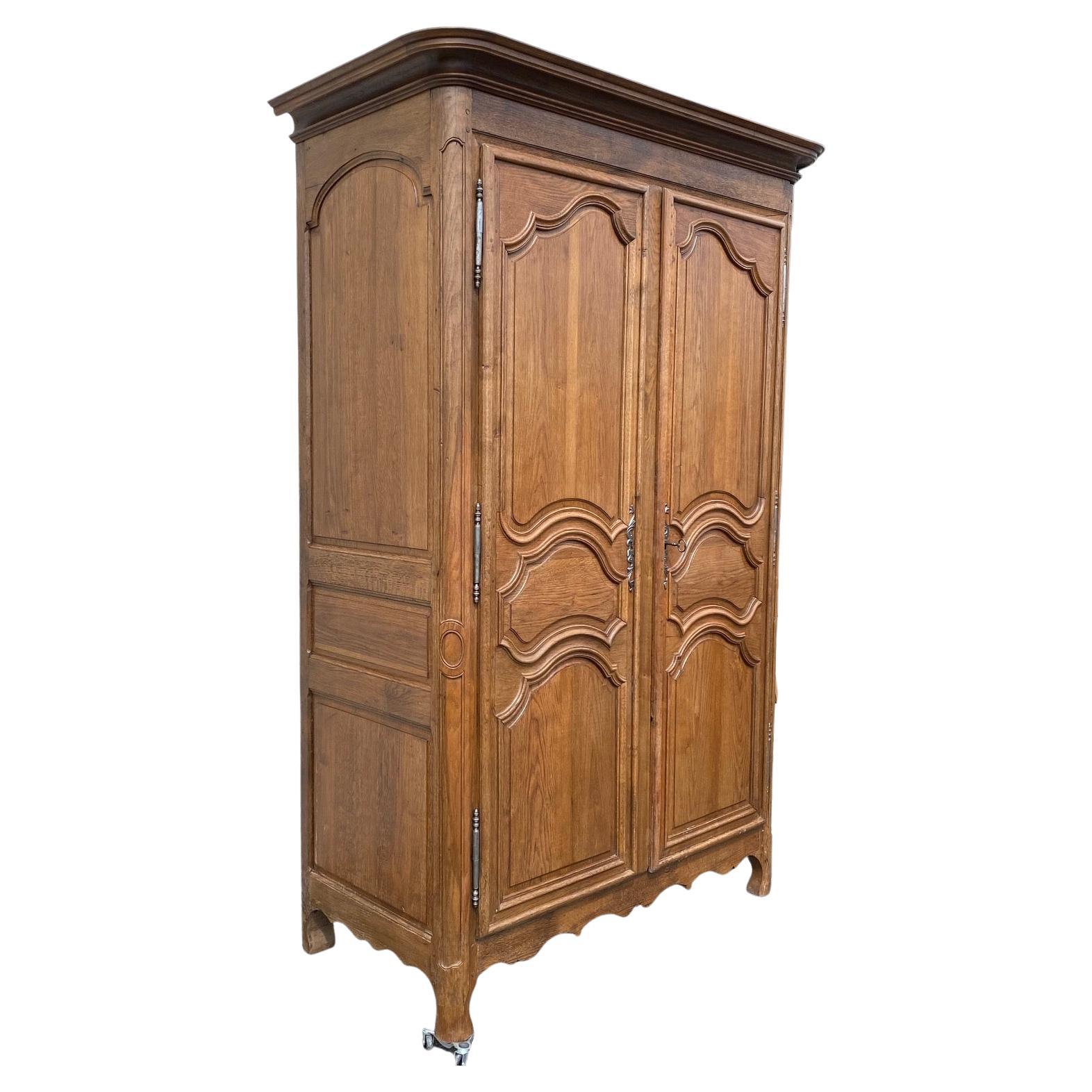 A very good quality carved walnut armoire originating from Normandy, France which was made during the early 19th century. The case consists of a carved frieze and paneled doors above a shaped apron.  Stunning brass escutcheon hardware with original