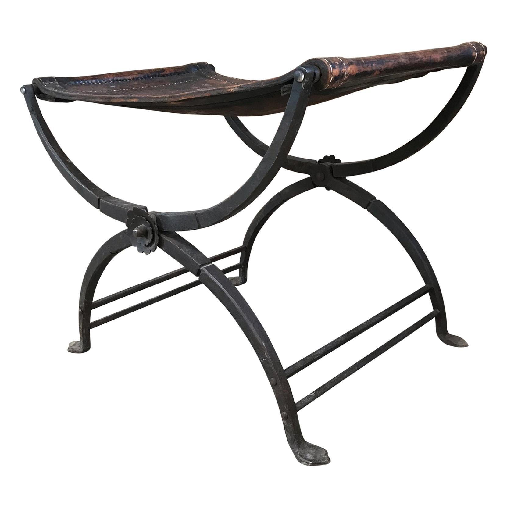 Curule Stool
France circa 1930s Curule Stool refined French Renaissance in Hand forged Iron with aged Saddle Leather. 
Elegant design and detail. Very heavy and solid. Unmarked. 
Dimensions: 17 D x 24.5 W x 19 H
Original Unrestored Vintage Preowned