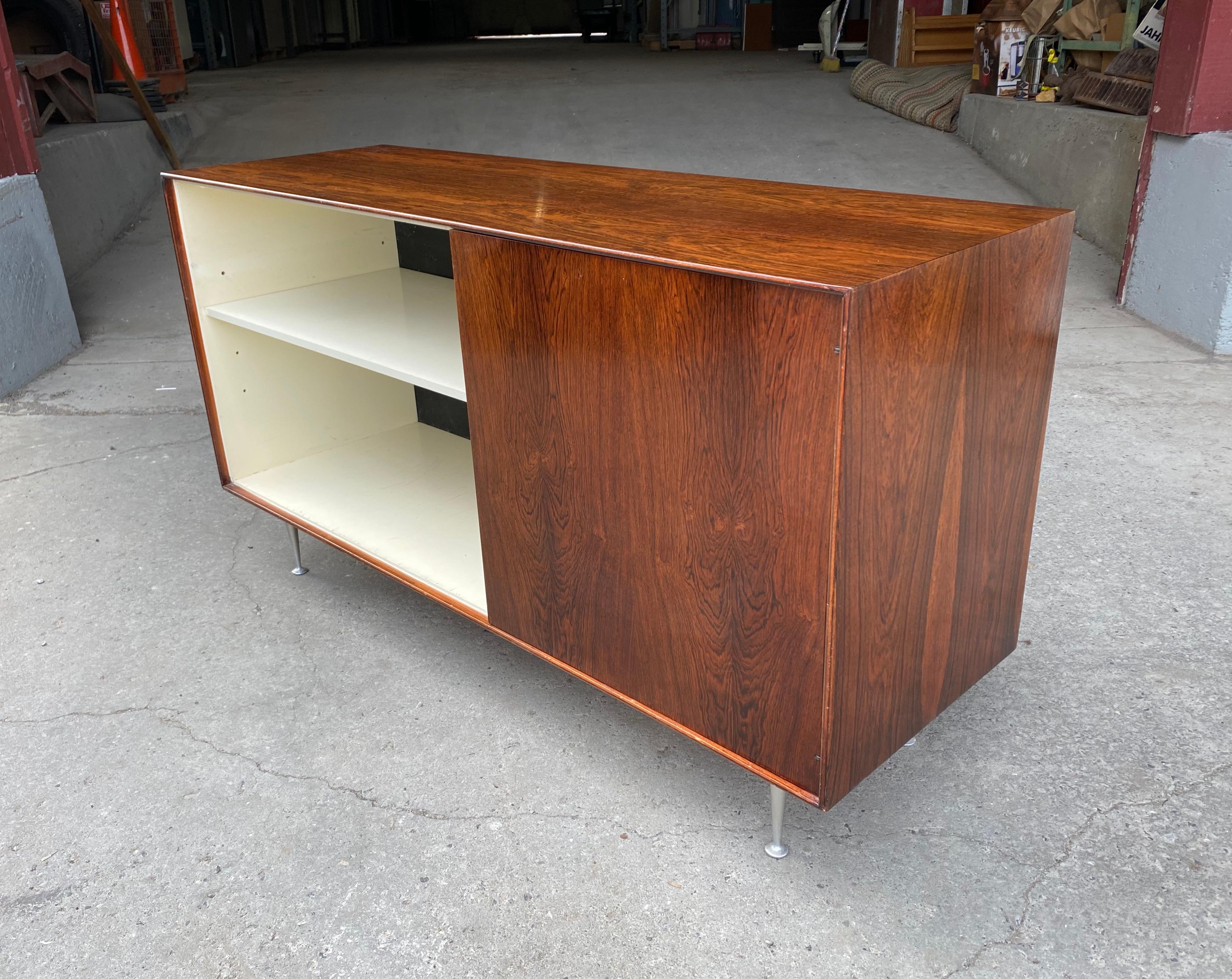 Classic George Nelson rosewood thin edge cabinet, manufactured by Herman Miller, sleek, simple, elegant rosewood cabinet. Left side, open storage / shelves, right side, door /shelves. Featuring Classic trademark George Nelson legs, beautiful