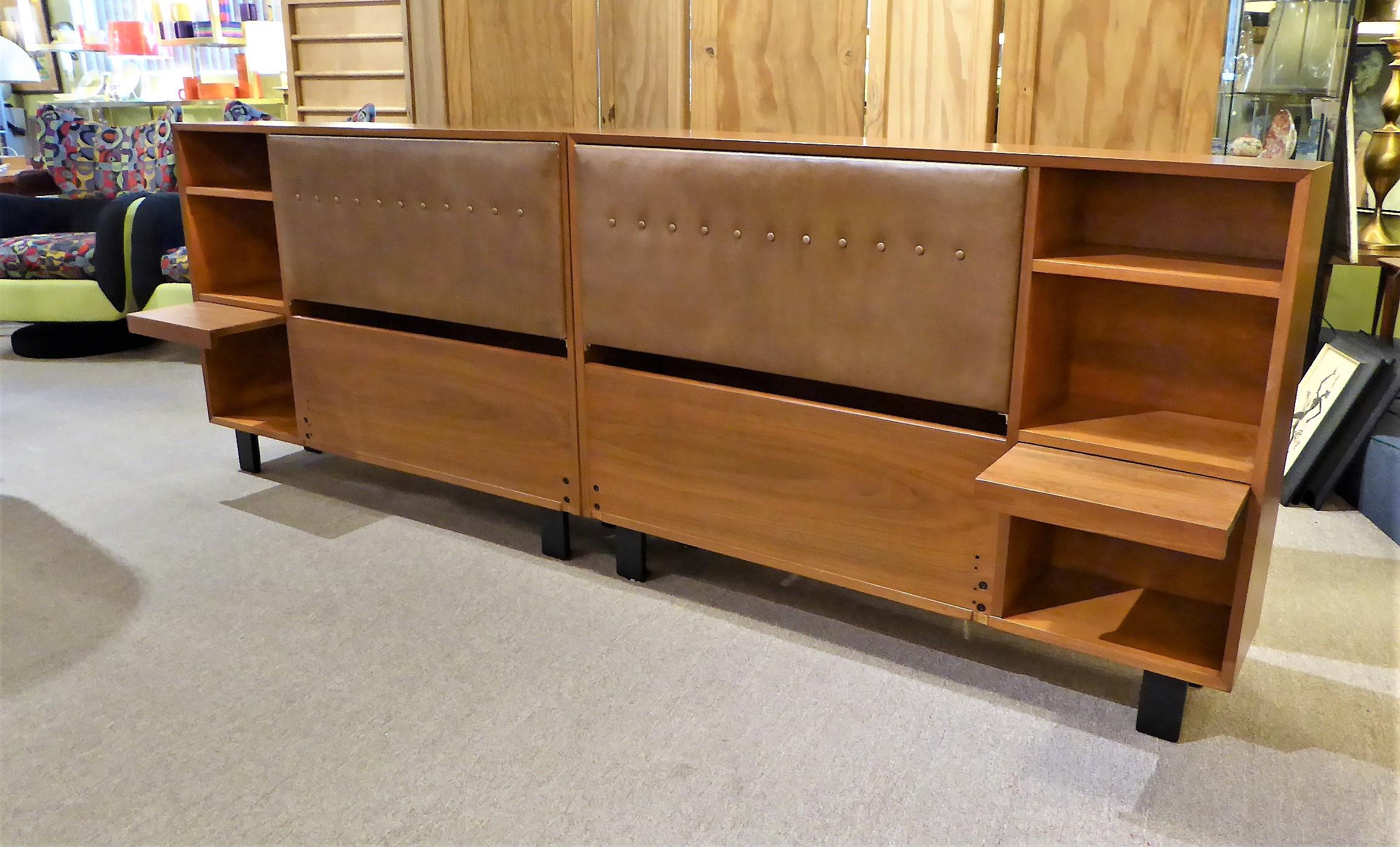 Smart and classic George Nelson design for the Herman Miller collection of the early 1950s, this pair of walnut King headboard storage units with bedside shelves and pull out tables are quite beautiful and utile. Consisting of a mirror image left