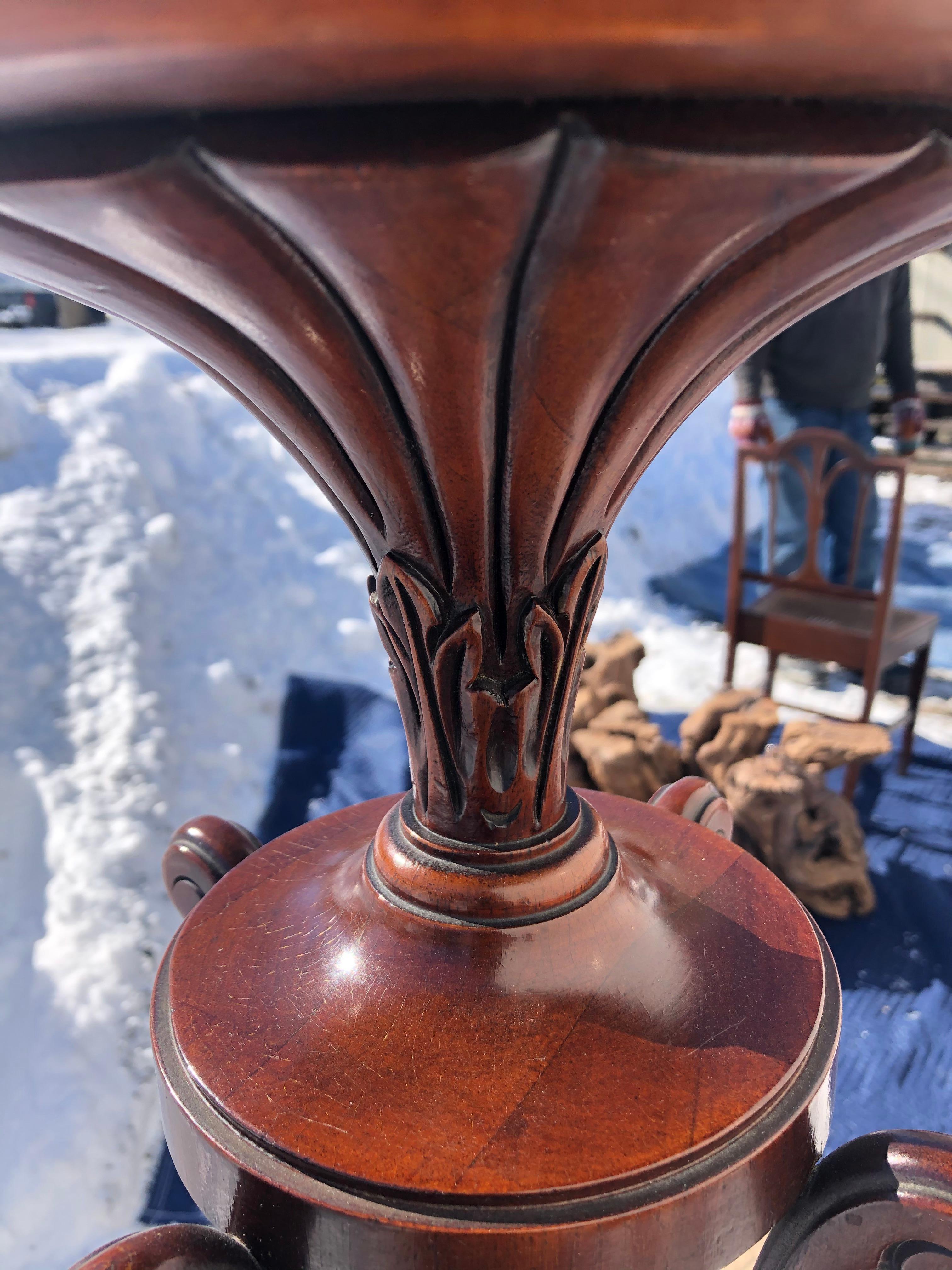 Georgian style carved mahogany plant stand column having a flared reeded vase form top with circular platform above a central carved baluster shaft enclosed by four rods terminating in scroll feet. The base has four acanthus carved cabriole legs and