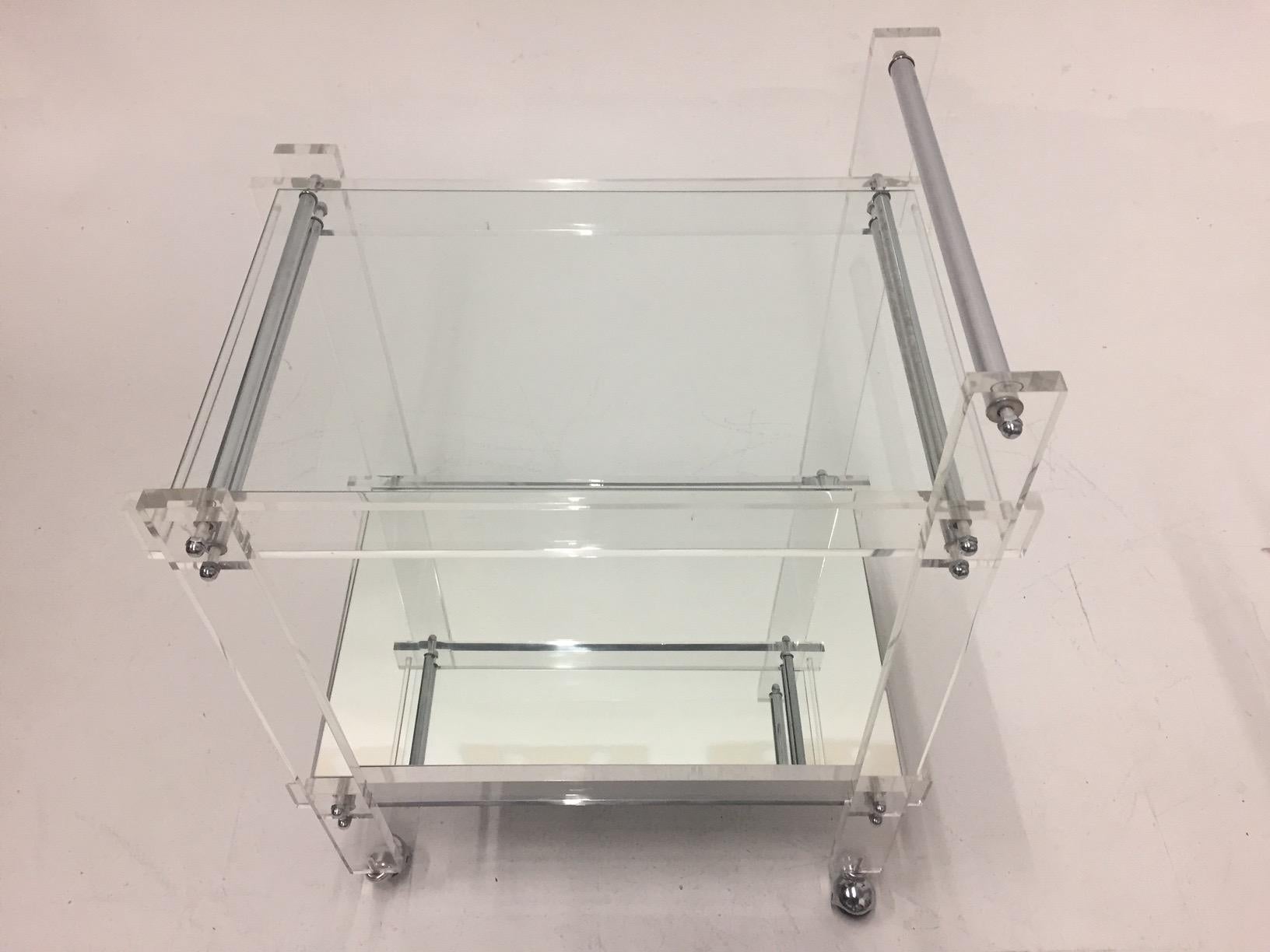 A glamorous vintage Lucite and chrome Mid-Century Modern bar cart having clear glass top tier and mirrored bottom shelf, easily rolled on chrome capped casters.
bottom shelf 11