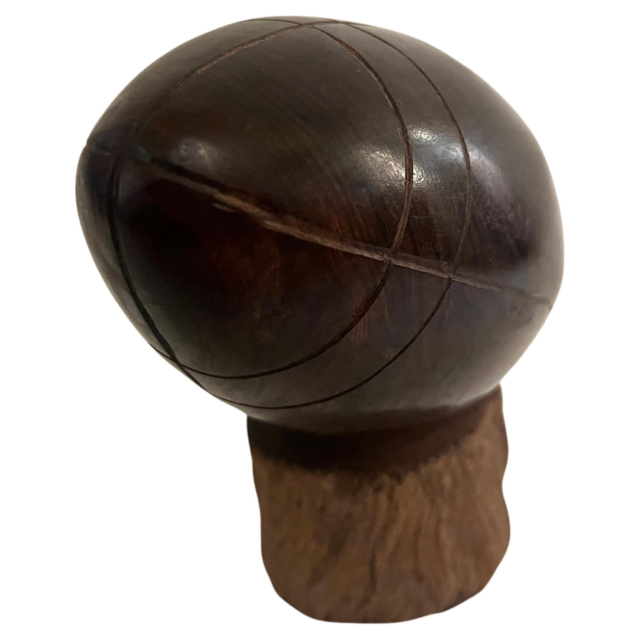 Magnifique ballon de football en bois de fer massif sculpté à la main vers les années 1970. Très bon état de conservation, ballon poli posé sur un piédestal, un classique des souvenirs américains.