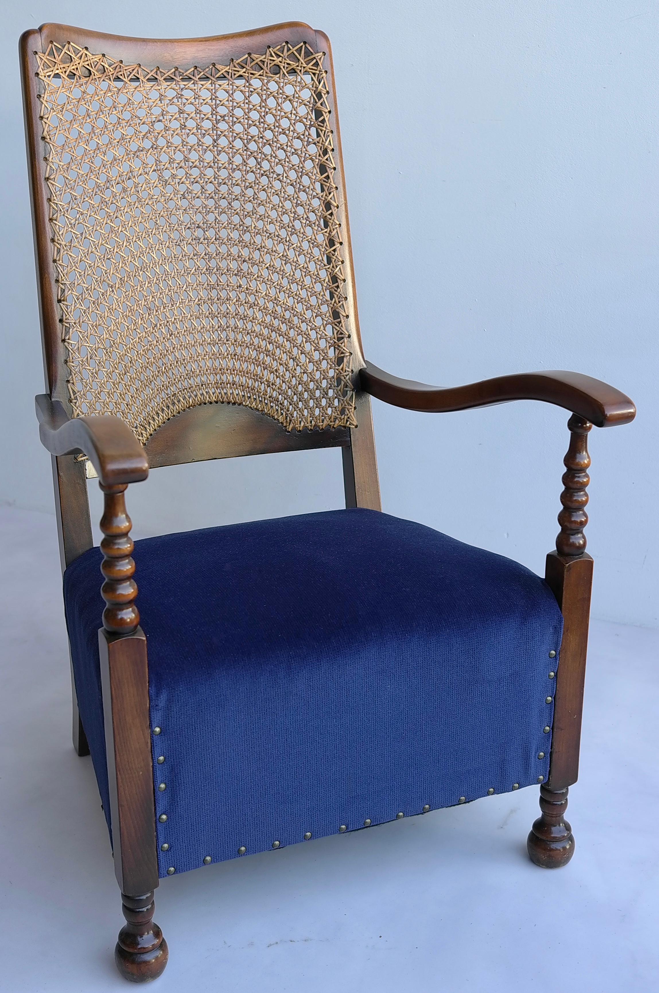 Classic highback lounge chair with blue seat and woven rattan back.