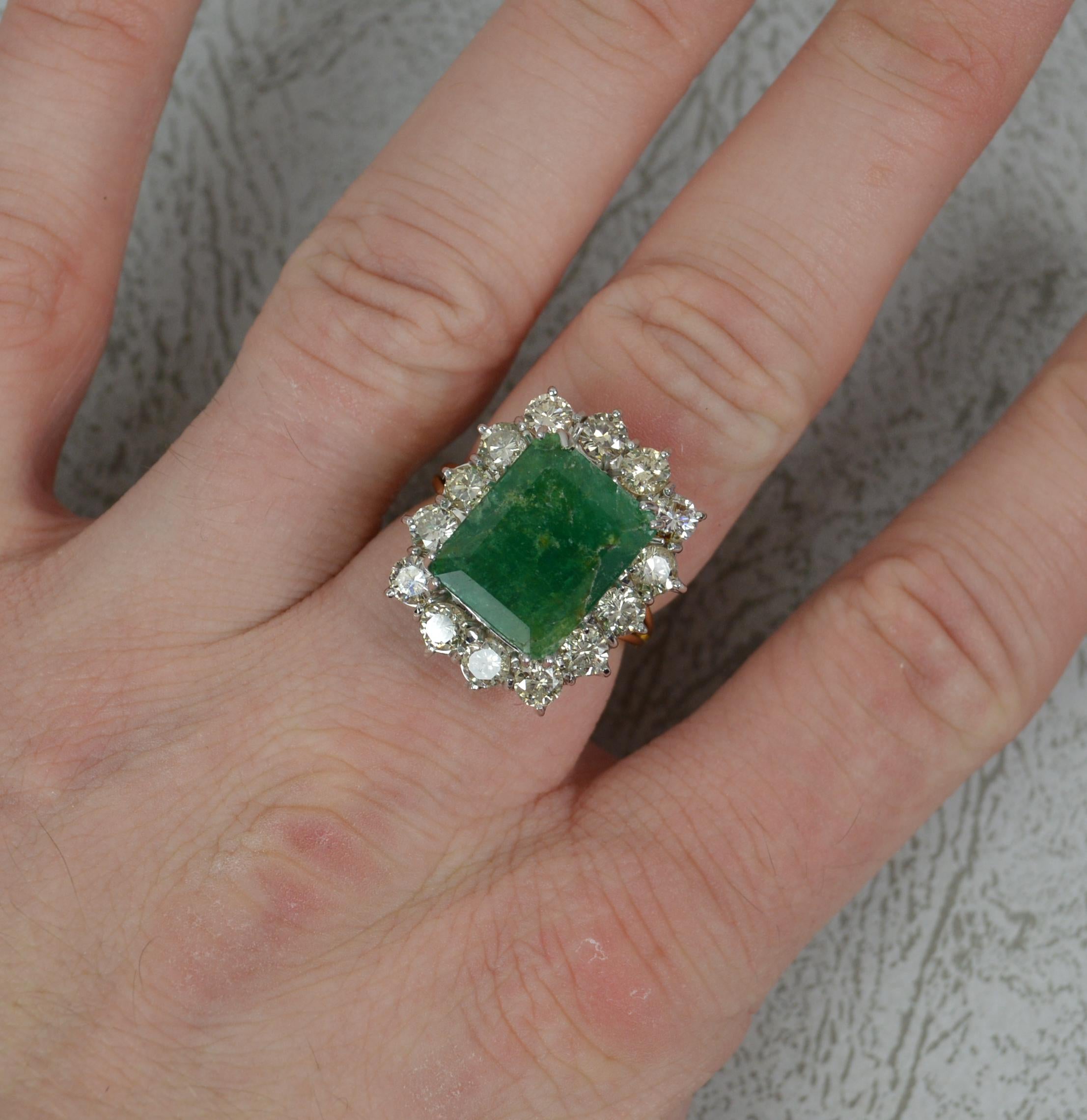 A superb Emerald and Diamond cluster ring.
Modelled in an 18ct yellow gold with a white gold head setting.
Designed with a very large emerald cut natural emerald to centre. 10.5mm x 13.1mm. Surrounding are fourteen round brilliant cut diamonds, all