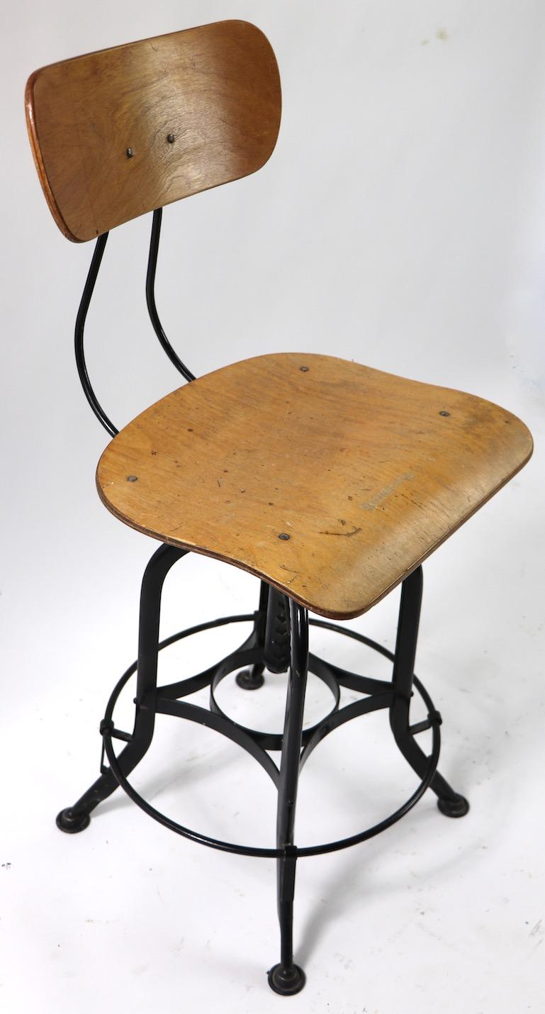 Possibly the most iconic piece of American Industrial School furniture, the Toledo swivel drafting, task, work stool in bent plywood and steel. This example is in very good, working condition, it swivels, adjusts in height, and the backrest is