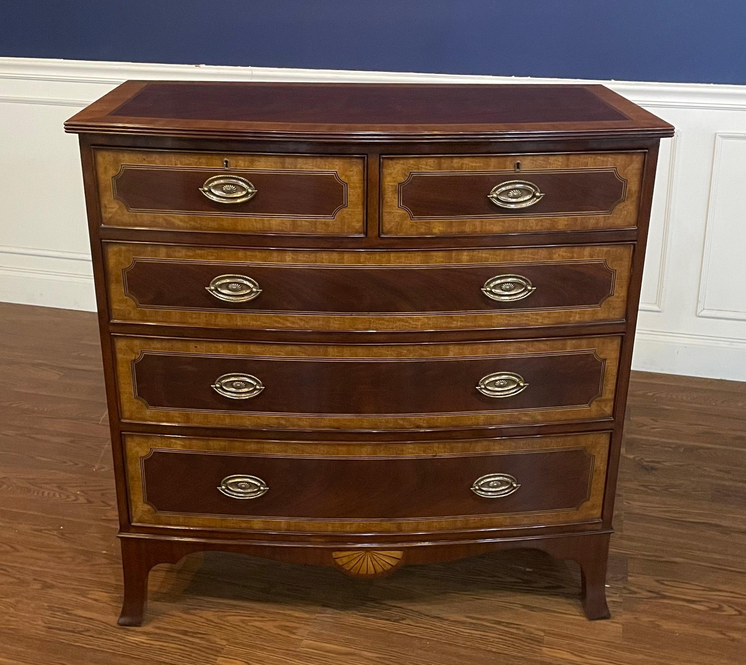 This is a classic mahogany inlaid bow front chest by Leighton Hall. Its design was inspired by chests from the early 1800s. It features five drawers, solid brass hardware and faux key holes. The drawer fronts have swirly crotch mahogany oval fields