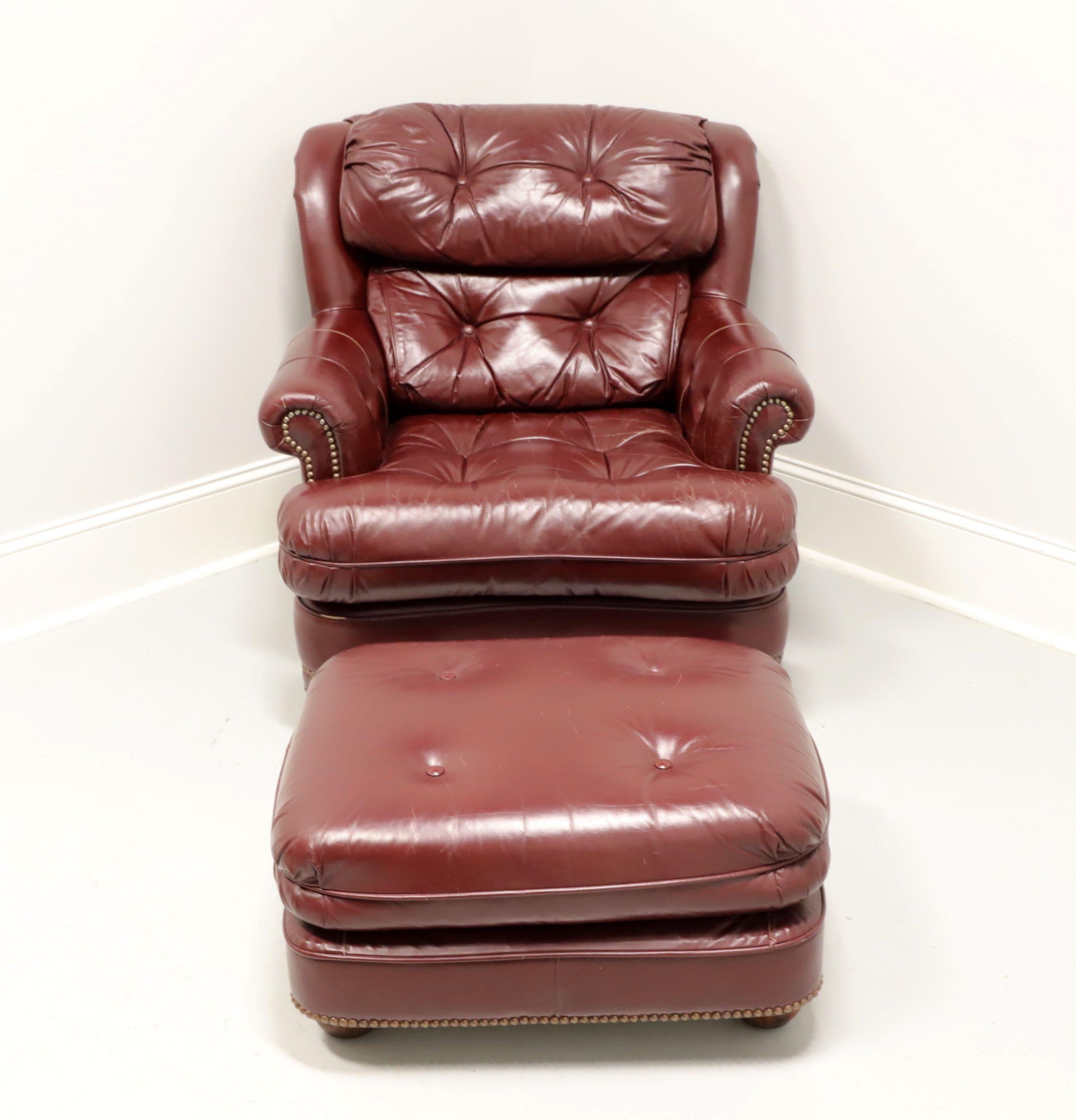 A Traditional style lounge armchair and ottoman by Classic Leather. Burgundy color button tufted top grain genuine leather upholstery and brass nailhead trim. Hardwood frame, wood bun feet on ottoman and front feet of chair. Made in Conover, North