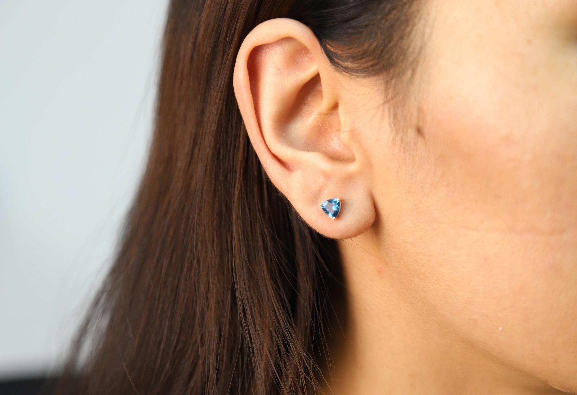 Decorate yourself in elegance with this Earring is crafted from 14-karat Yellow Gold by Gin & Grace Earring. It creates a contemporary look with these sparkling London Blue Topaz stud earrings. This Earring is made up of 6MM Trillion-Cut Prong