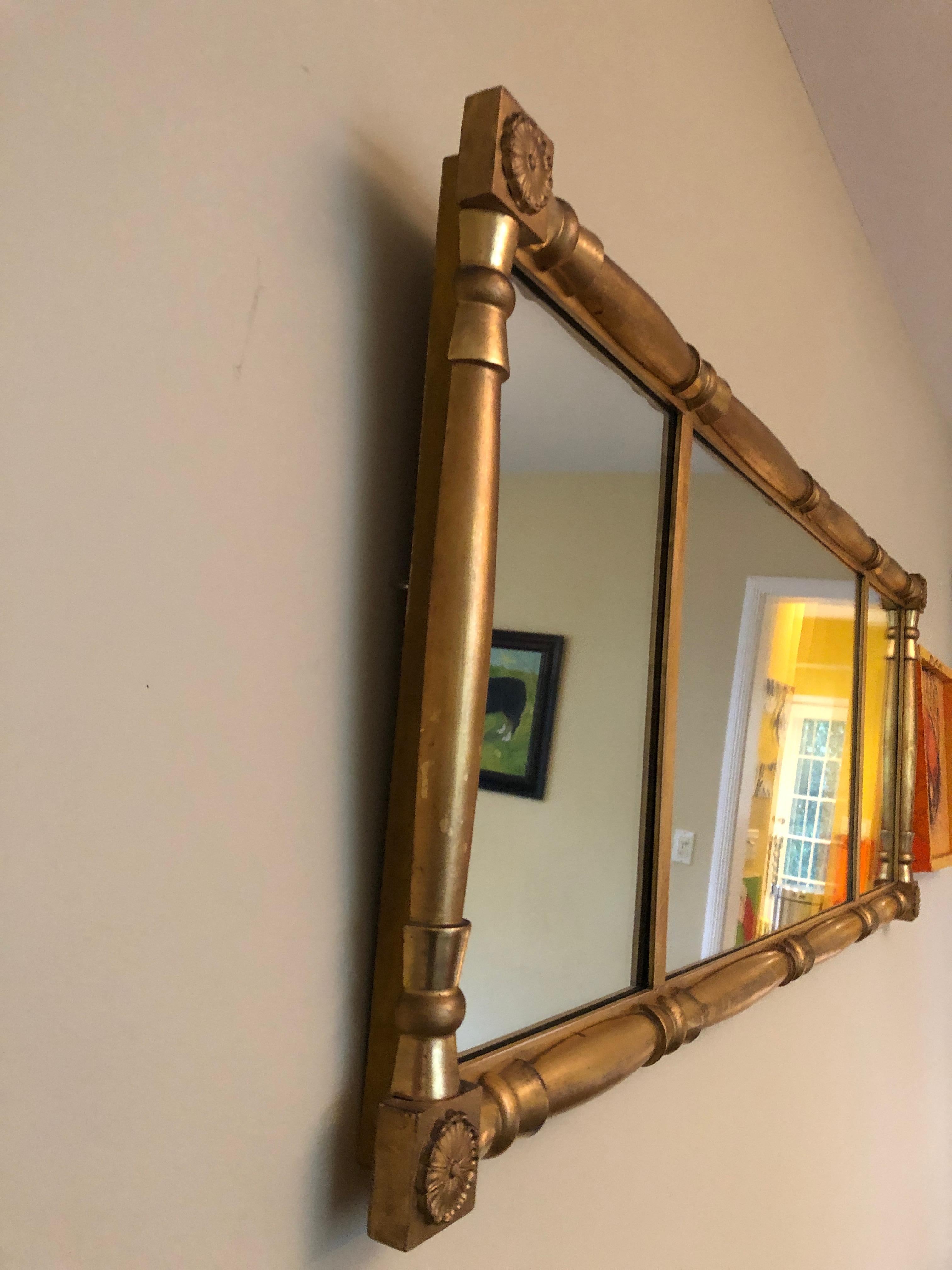 Classic long horizontal mirror having neoclassical giltwood frame with rosettes in the corners and bevelled mirror.