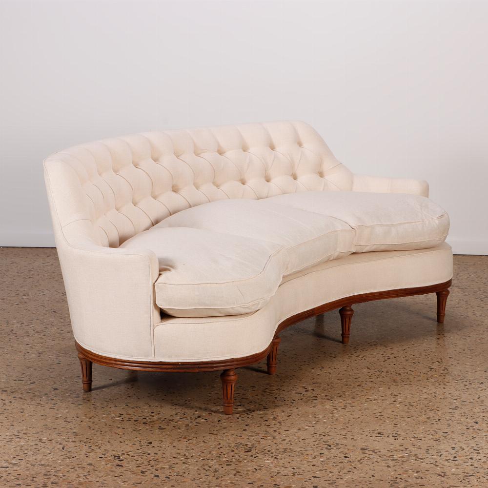 Sofá clásico de lujo con respaldo curvado y acolchado, C 940. El diseño perfilado es moderno, con el tradicional acolchado de botones sobre tres asientos profundos y patas de madera cortas, torneadas y estriadas. Recientemente retapizada con tela
