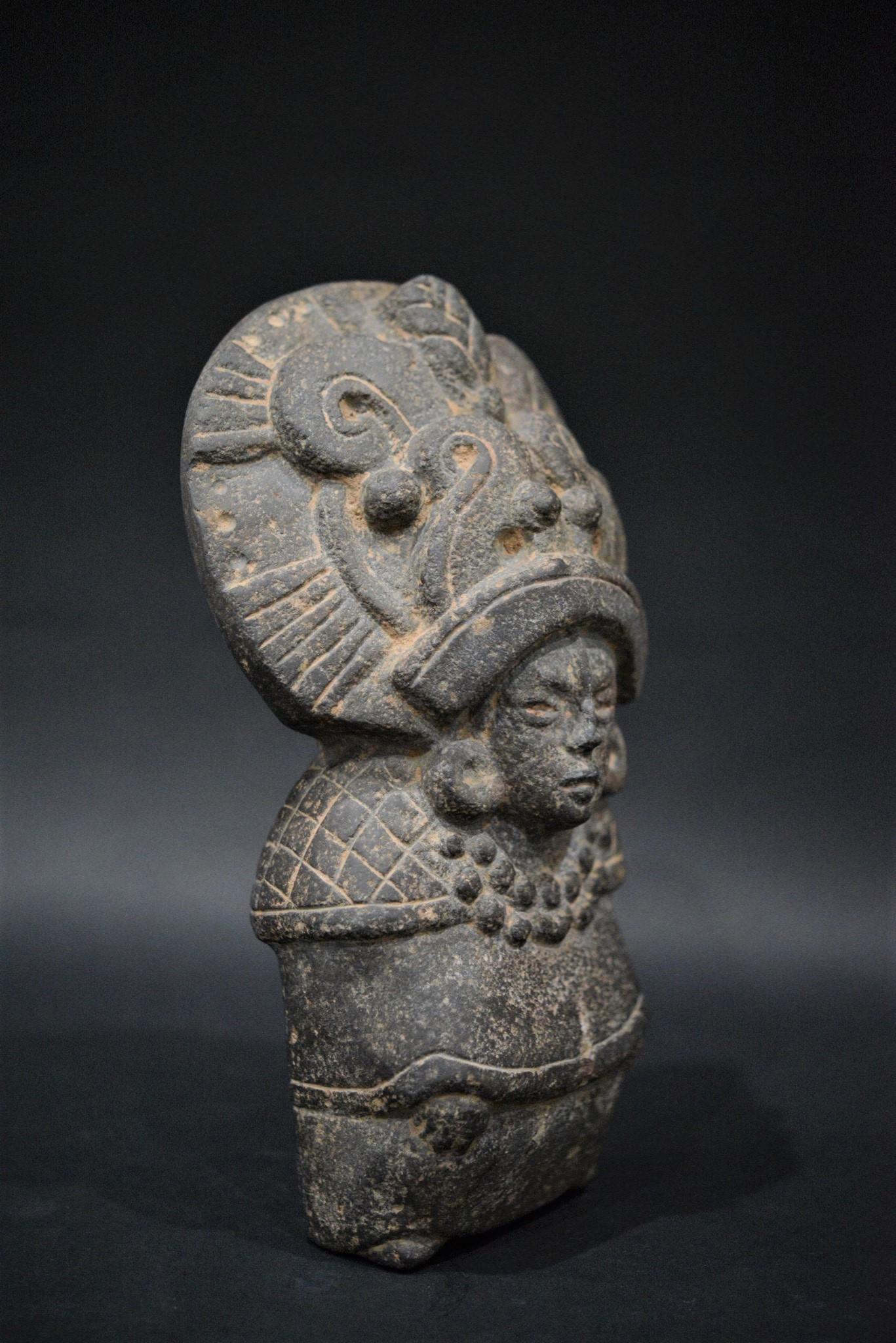 A superb basalt sculpture of an early Maya Goddess, wearing a splendid and oversize headdress, large earflares, and a beaded necklace with a pendant(surely jade).

Her shoulders are covered with a checkered shawl (Quechquemitl), her hands are