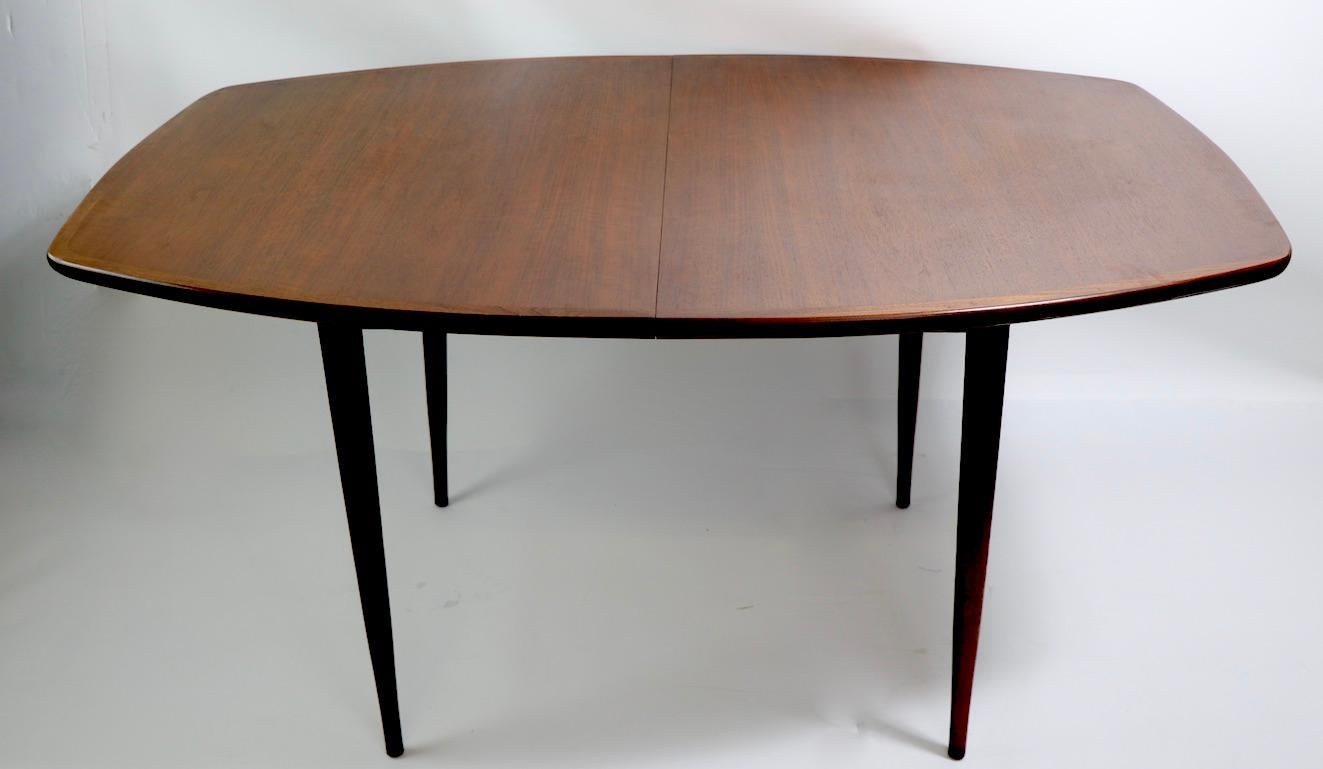 Classic mid century dining table, well crafted of solid wood, with elegant architectural lines, clean, original, ready to use condition. The table has two original leaves each 18. W with both leaves in place 94 inch x W without leavers 58 inches.