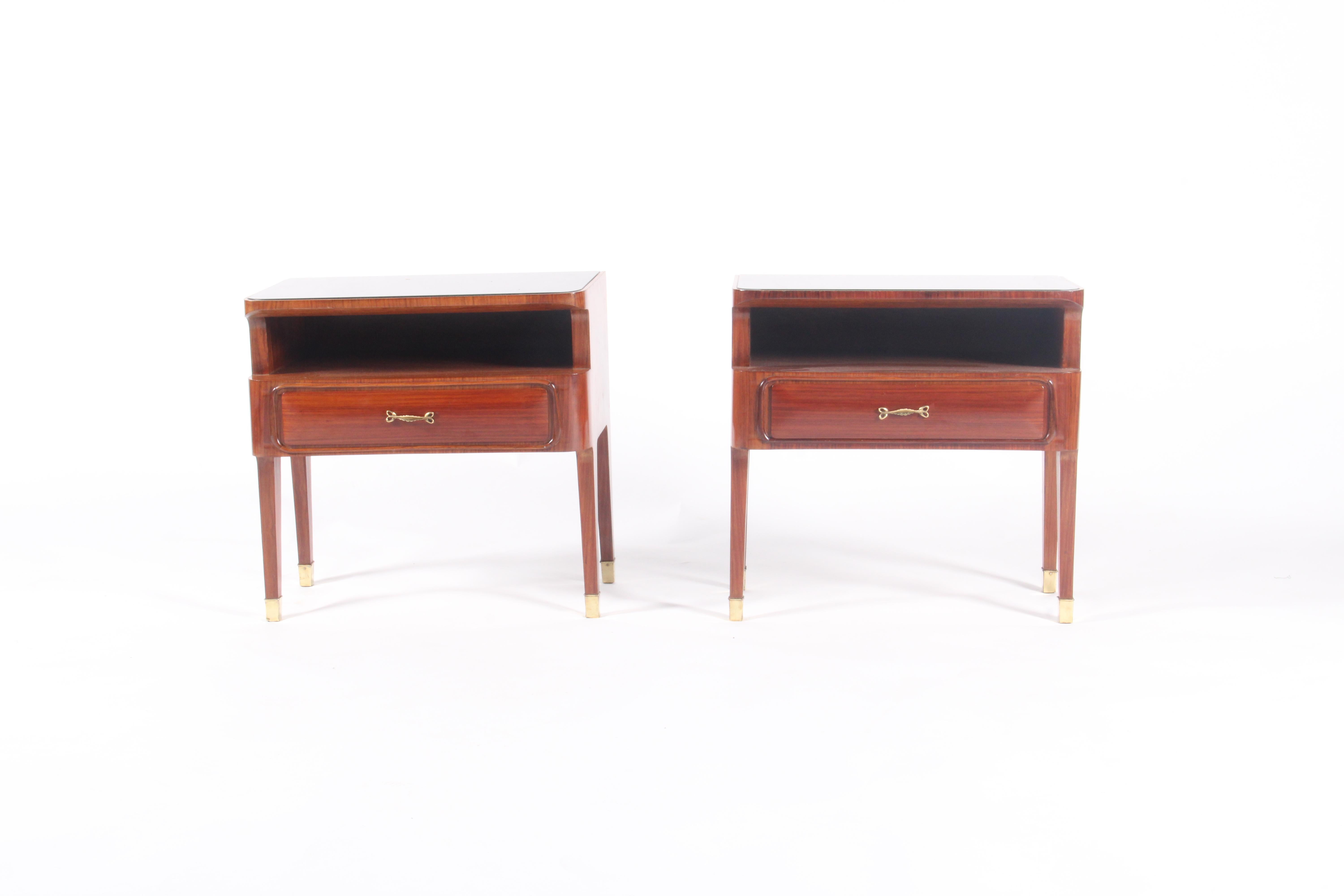 Introduce timeless sophistication to your bedroom with this stunning pair of mid-century Italian bedside tables—an exceptional showcase of 1950s design. Crafted in richly grained rosewood, each piece features a sleek black inset glass top that adds